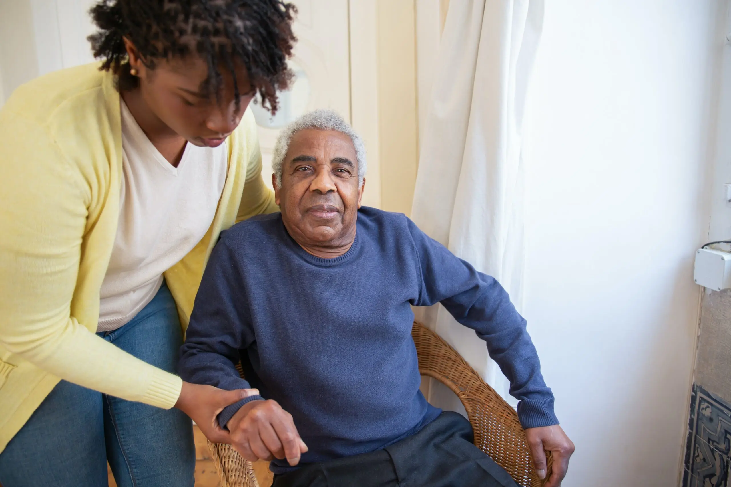 A woman helping an older man to stand up