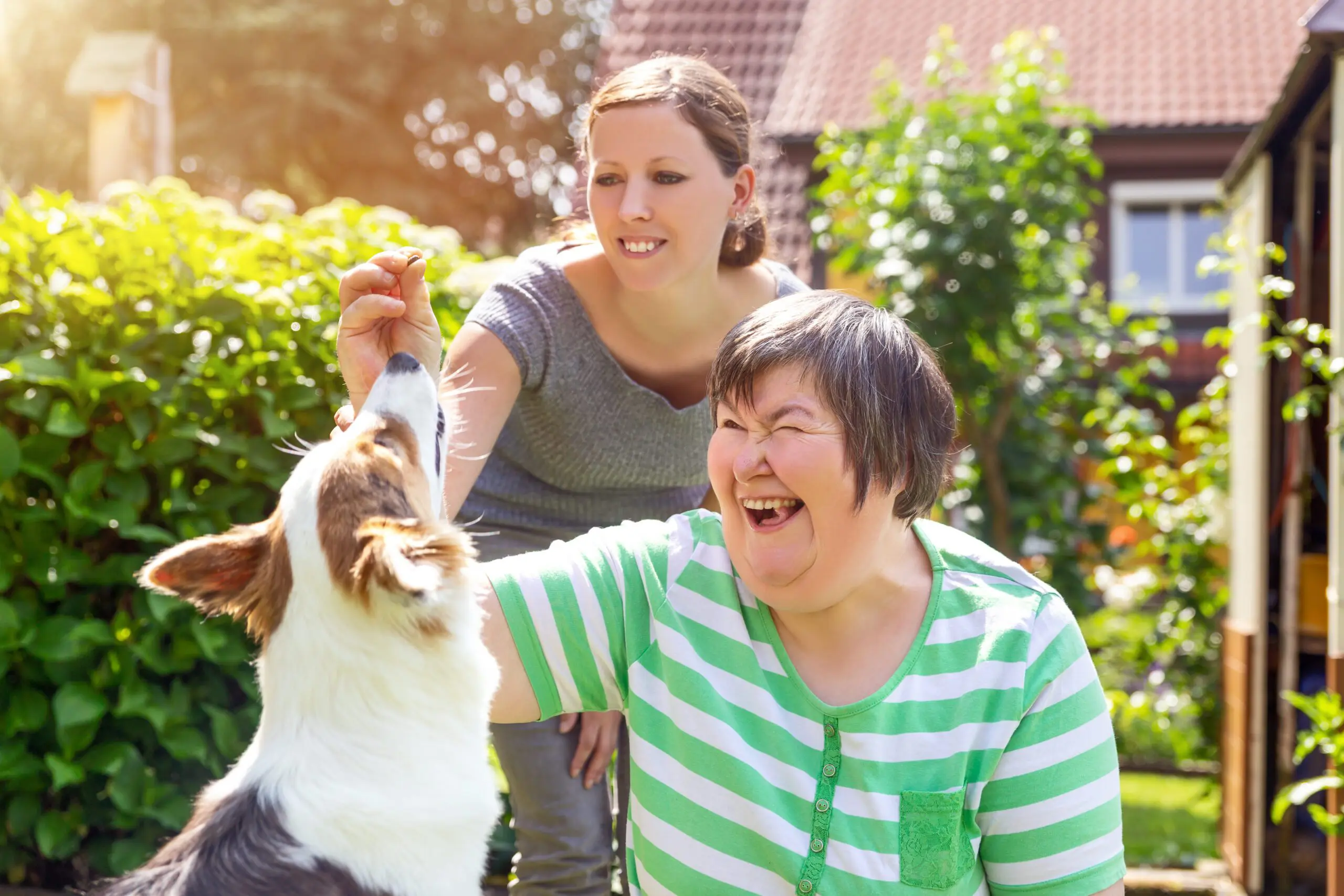 A pair of women giving a treat to a dog