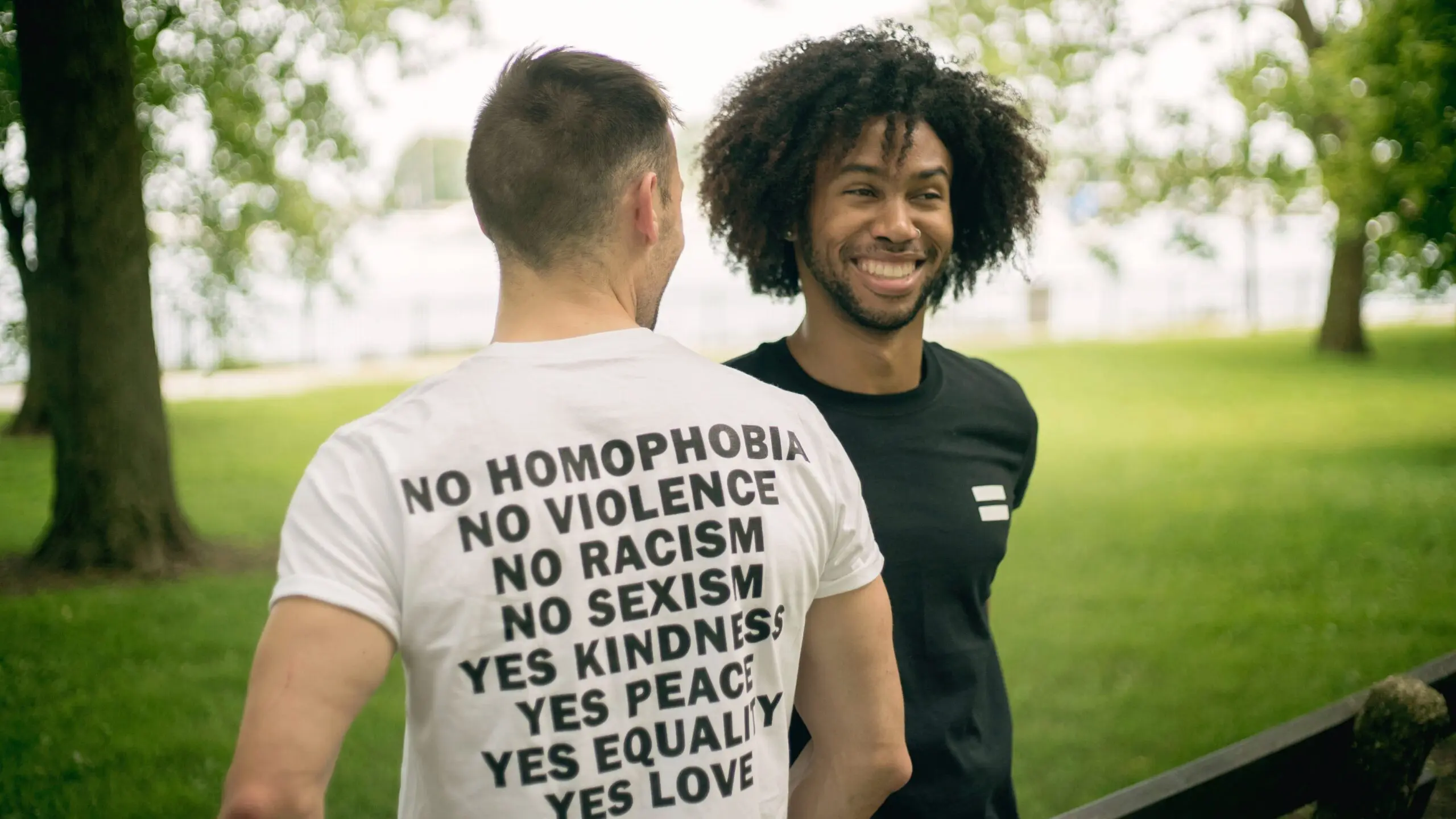 Two people in a park, one is wearing an anti-bigotry shirt