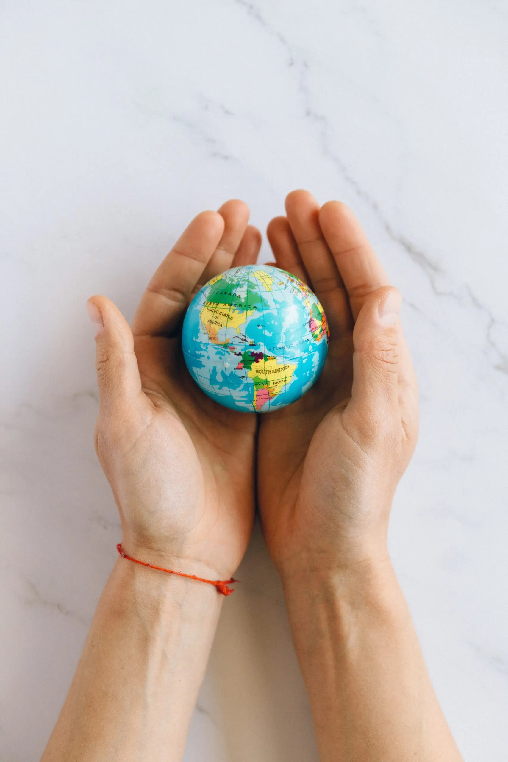 A small globe being held in a pair of hands