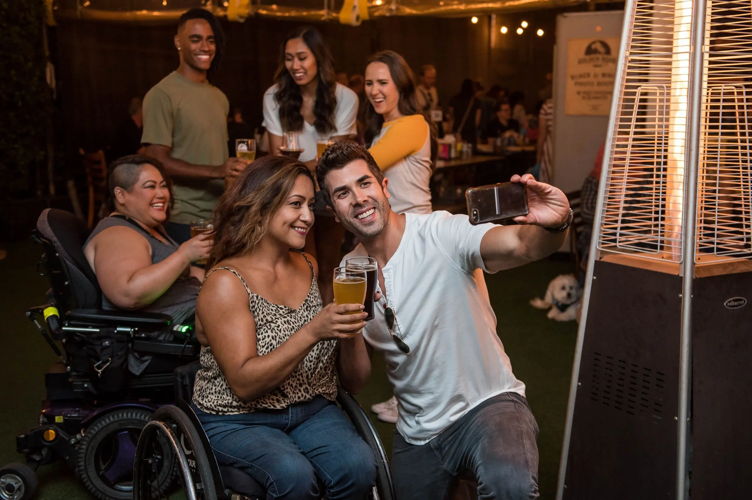 Five people in a bar drinking, two of them in wheelchairs