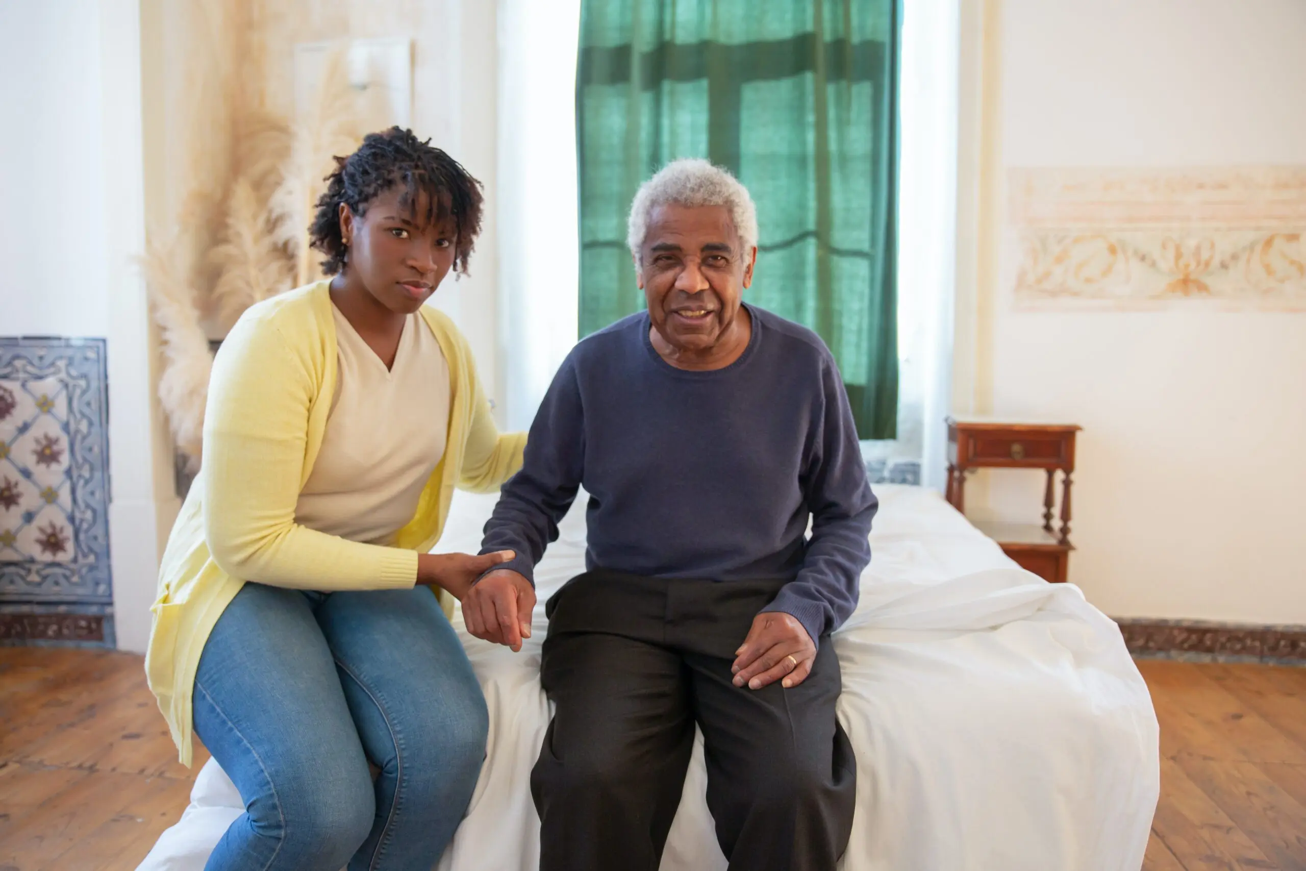 Two people sat on a bed, holding hands