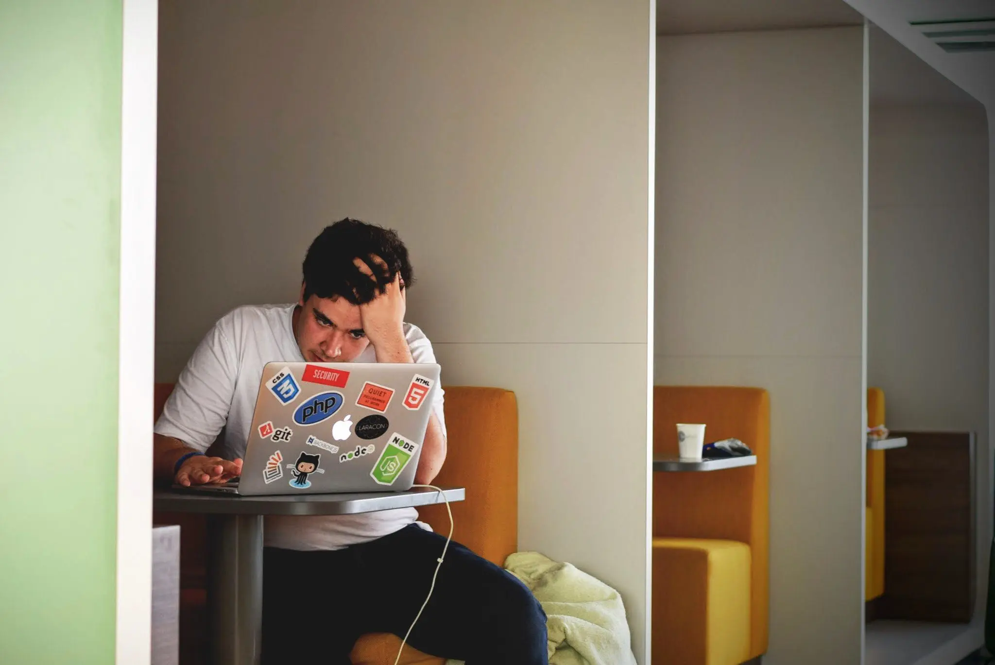 A person with their head in their hand staring at a laptop screen