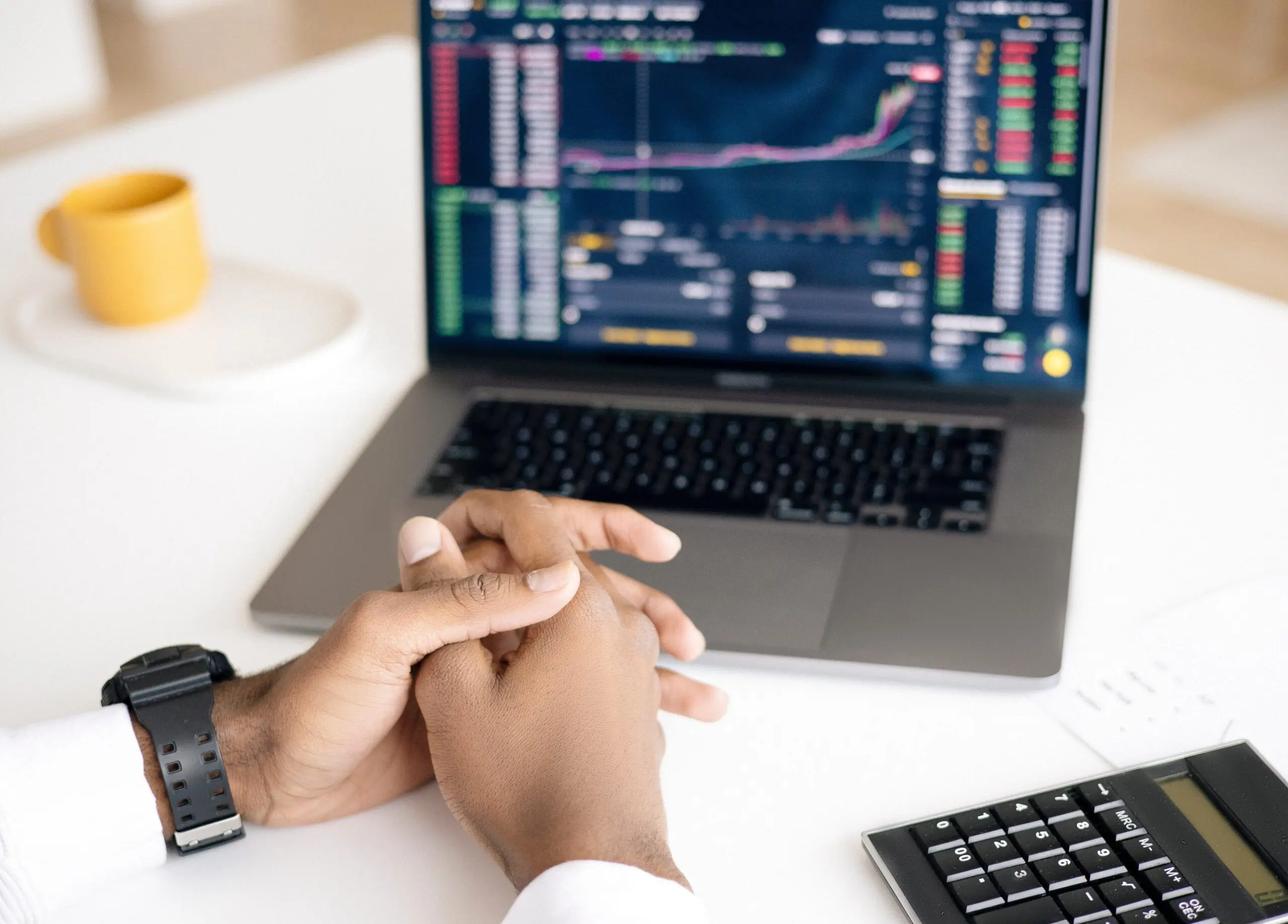 A pair of clasped hands next to a laptop
