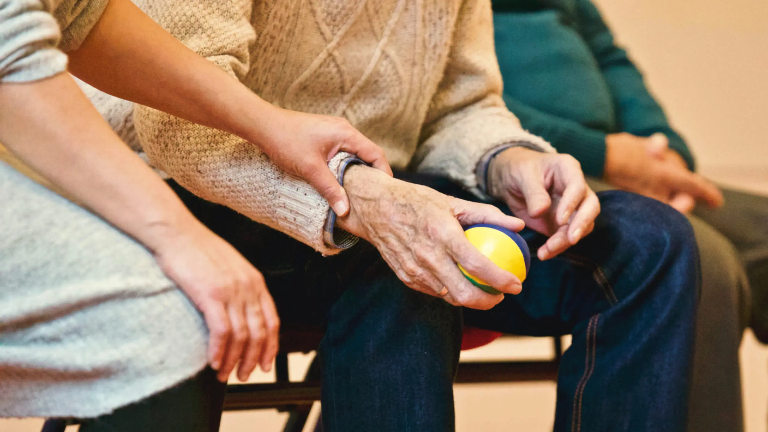 An image of someone holding a ball, while someone else holds their wrist