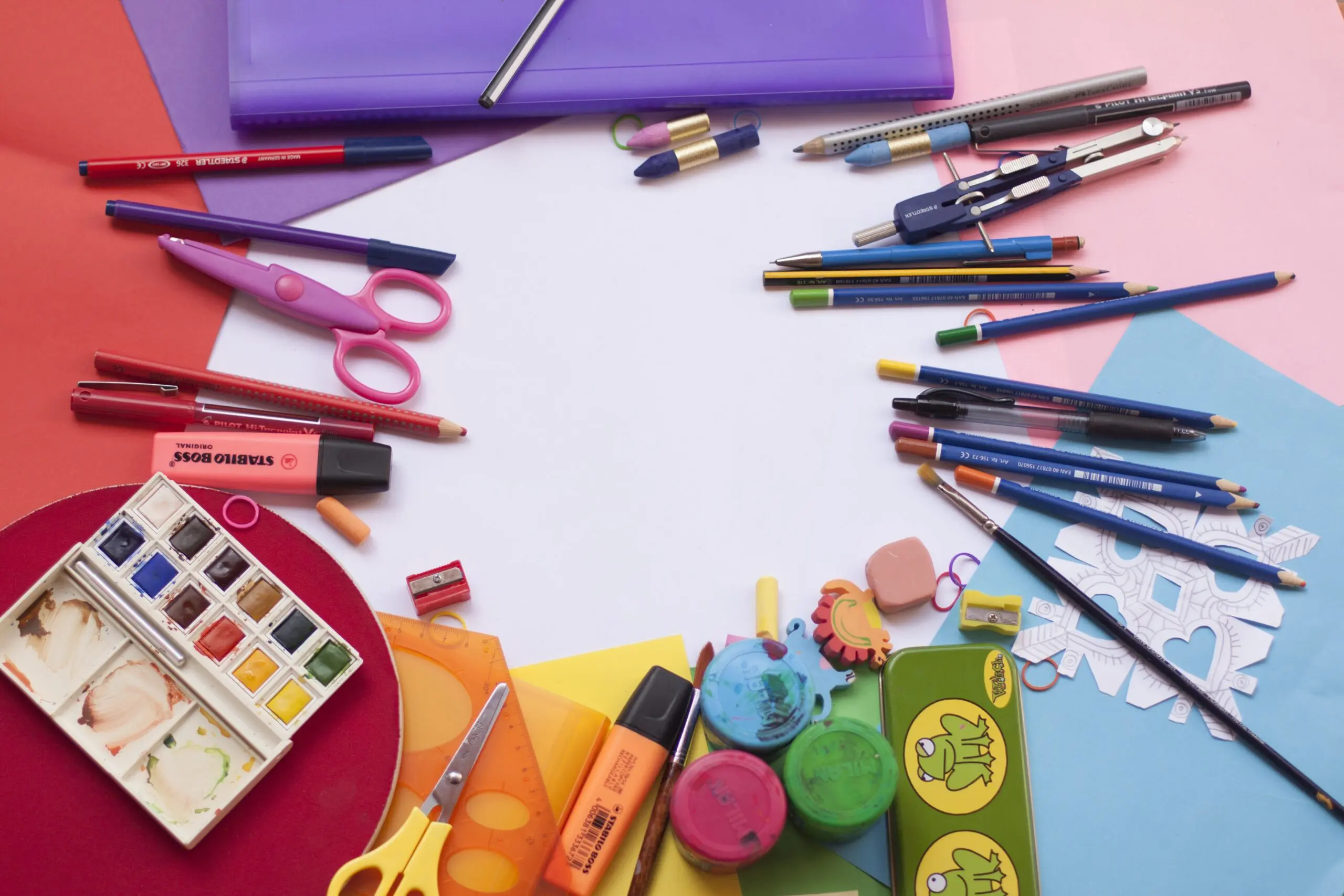 A white circle, surrounded by different coloured paper, and art supplies