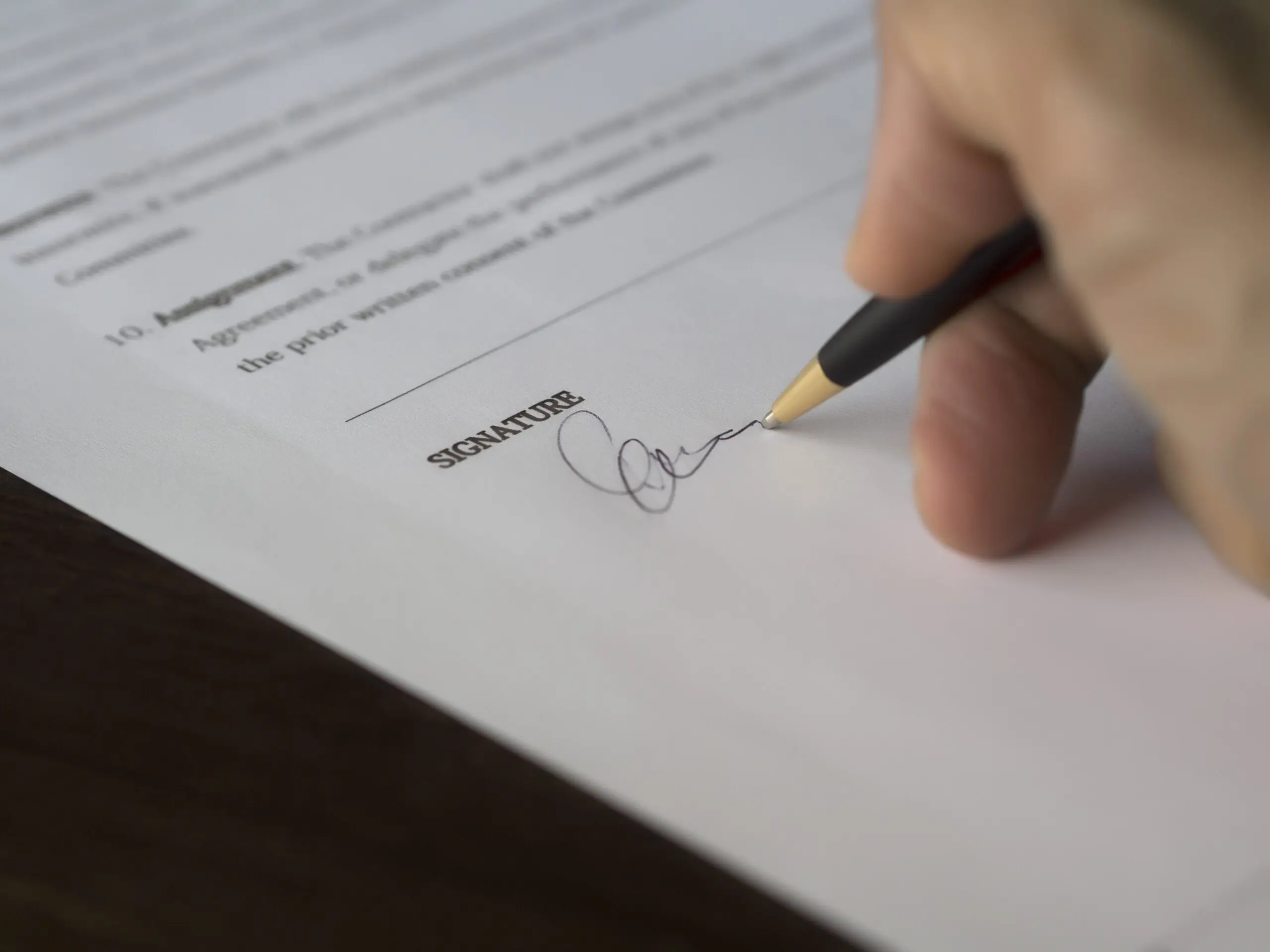 Somebody writing their signature on a piece of paper