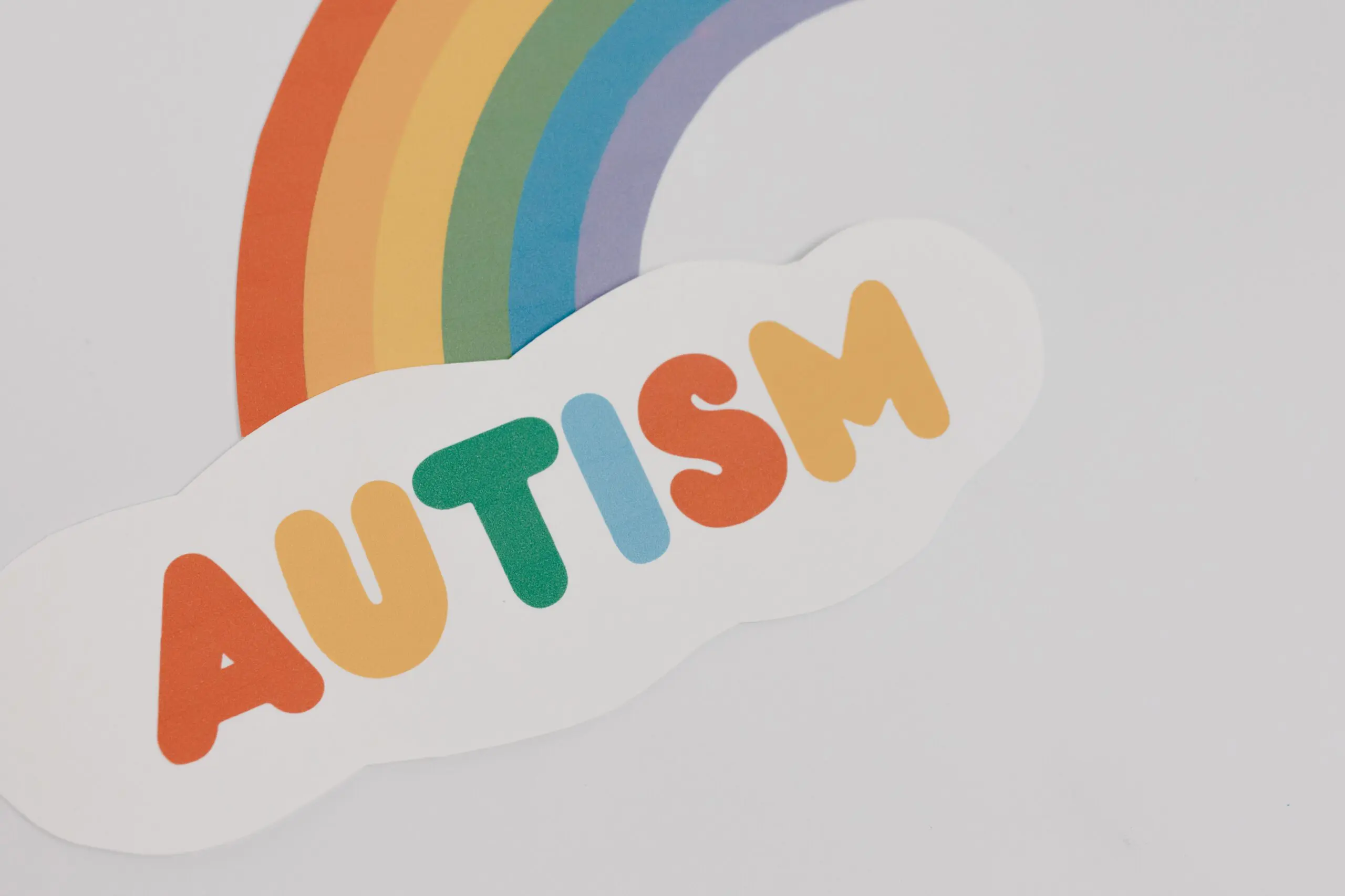 The word autism in colours with a rainbow coming off of it