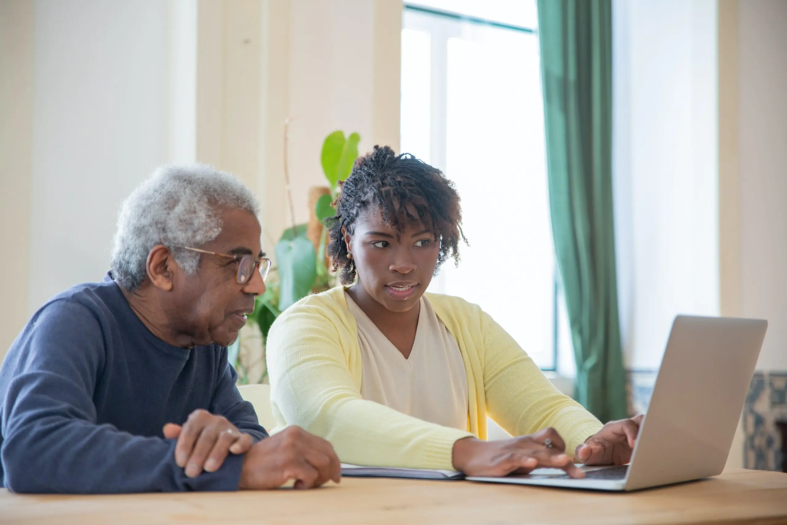 A woman showing an older man something on a laptop