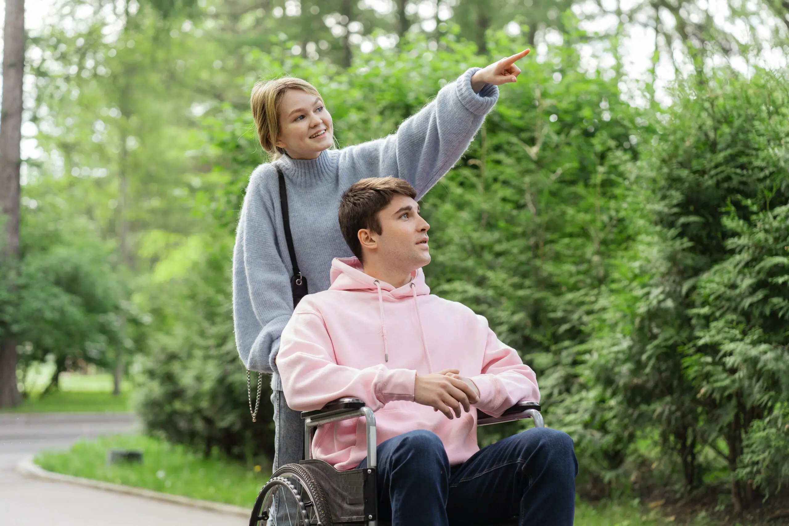 A woman pointing something out to a man in a wheelchair