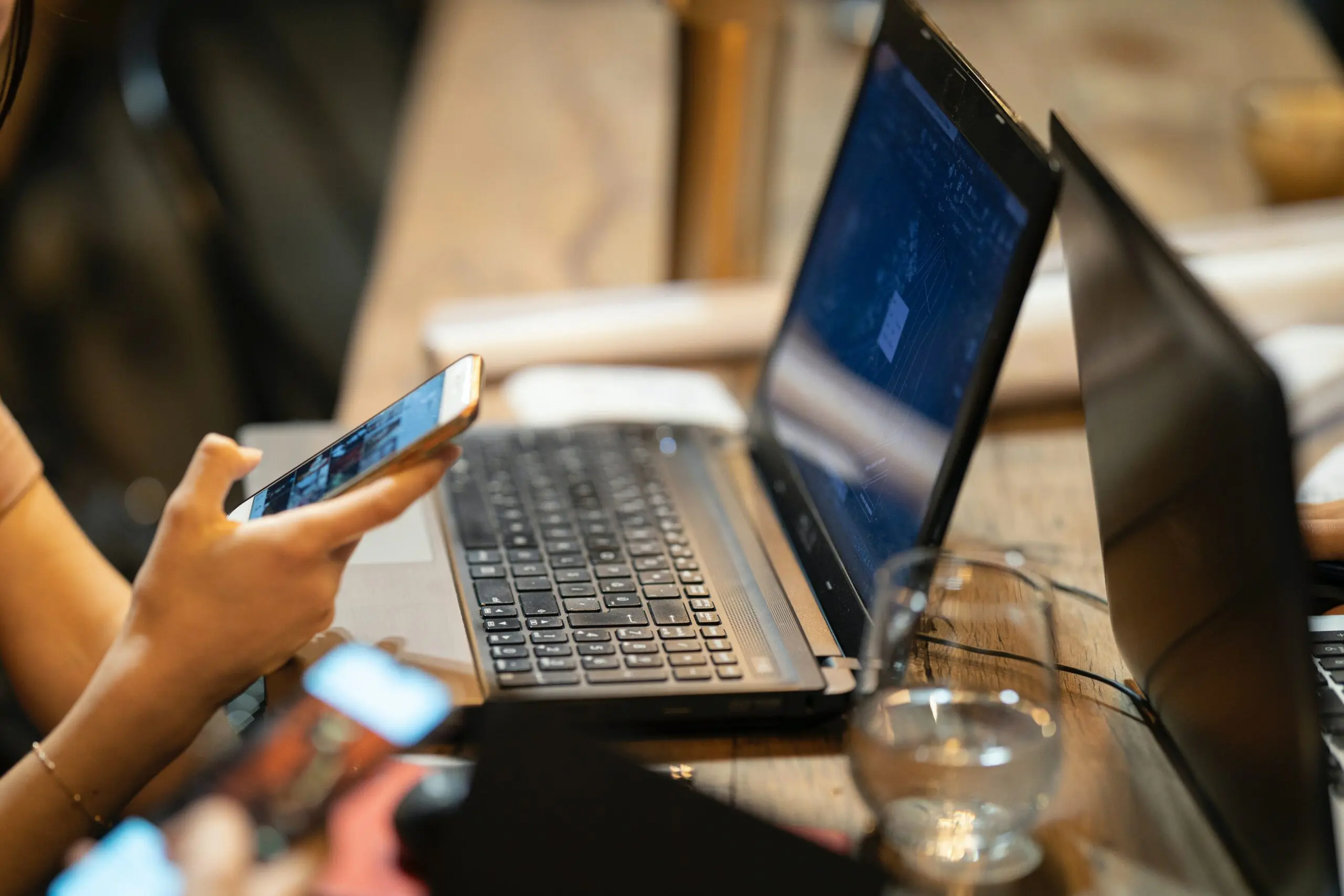 Someone looking at their phone while using a laptop
