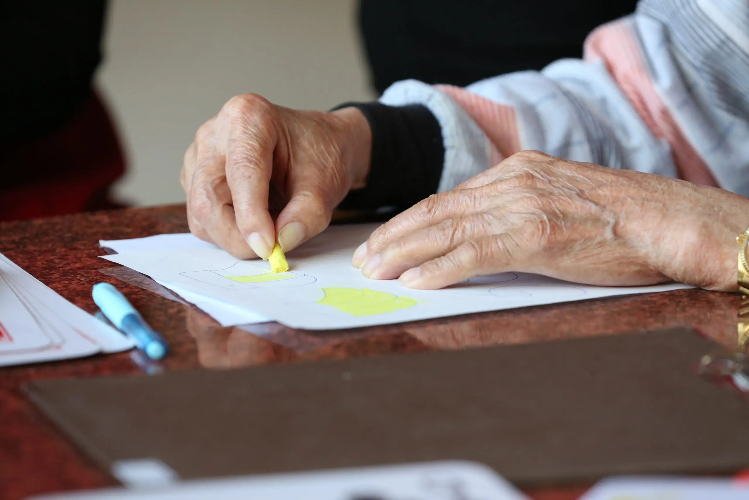An older person colouring in a shape with a crayon