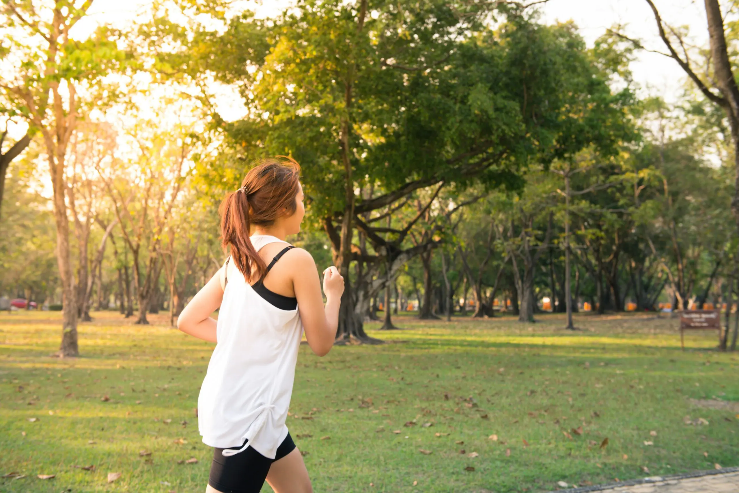 A woman running beside a forest