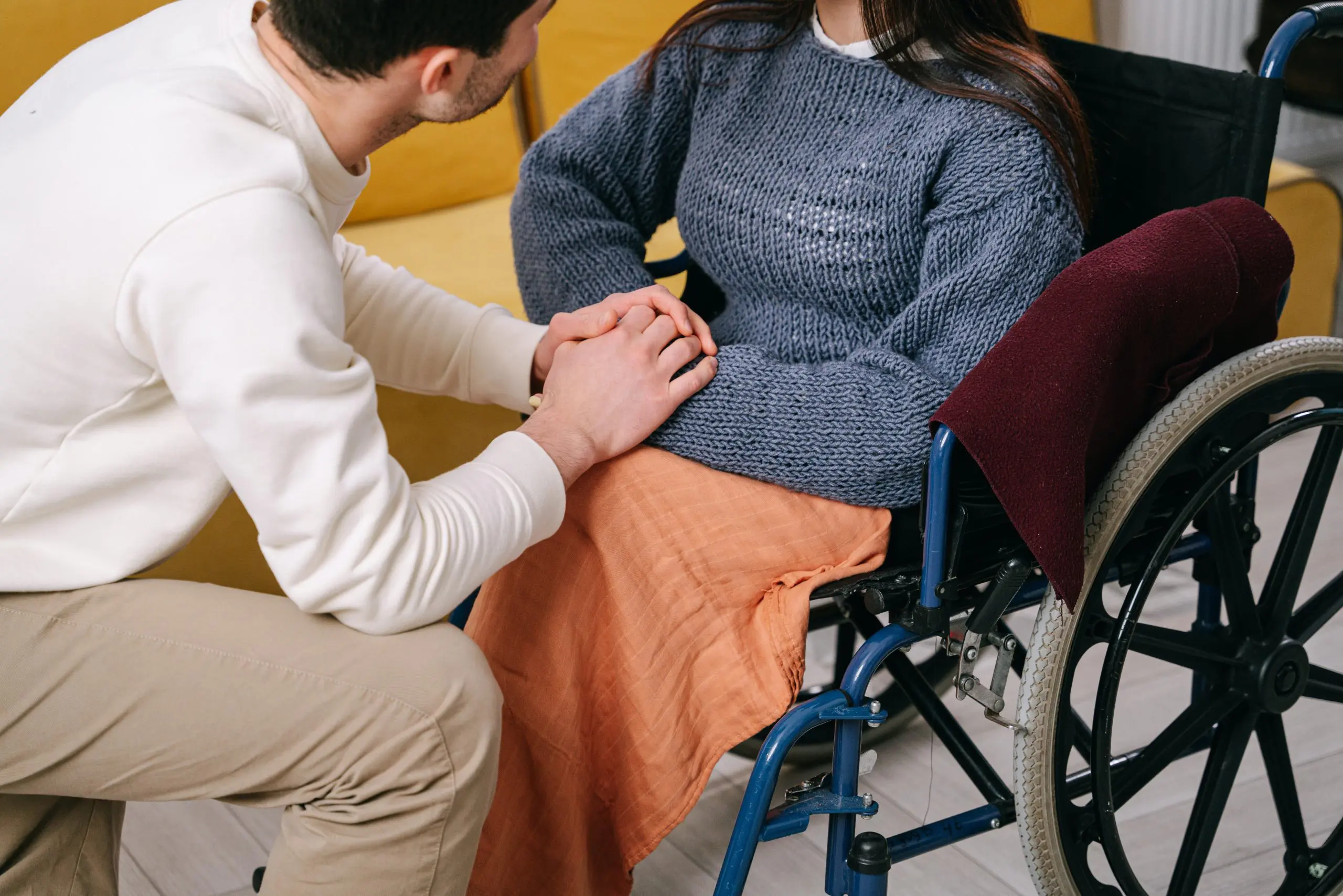 Two people, one in a wheelchair, clasping hands