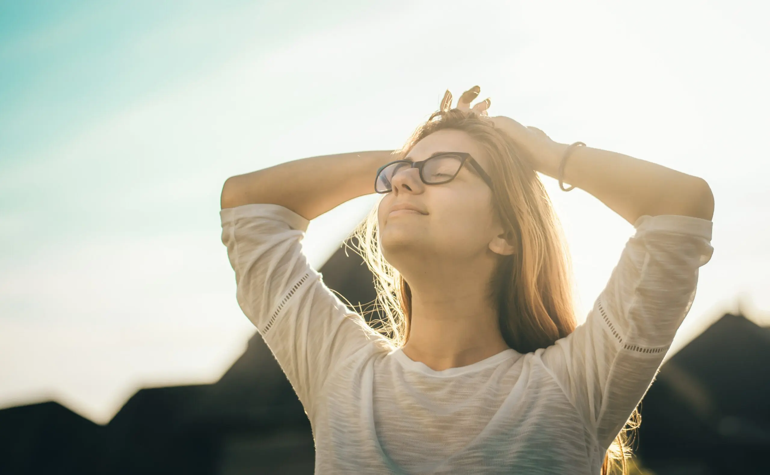 A smiling woman with her hands behind her head