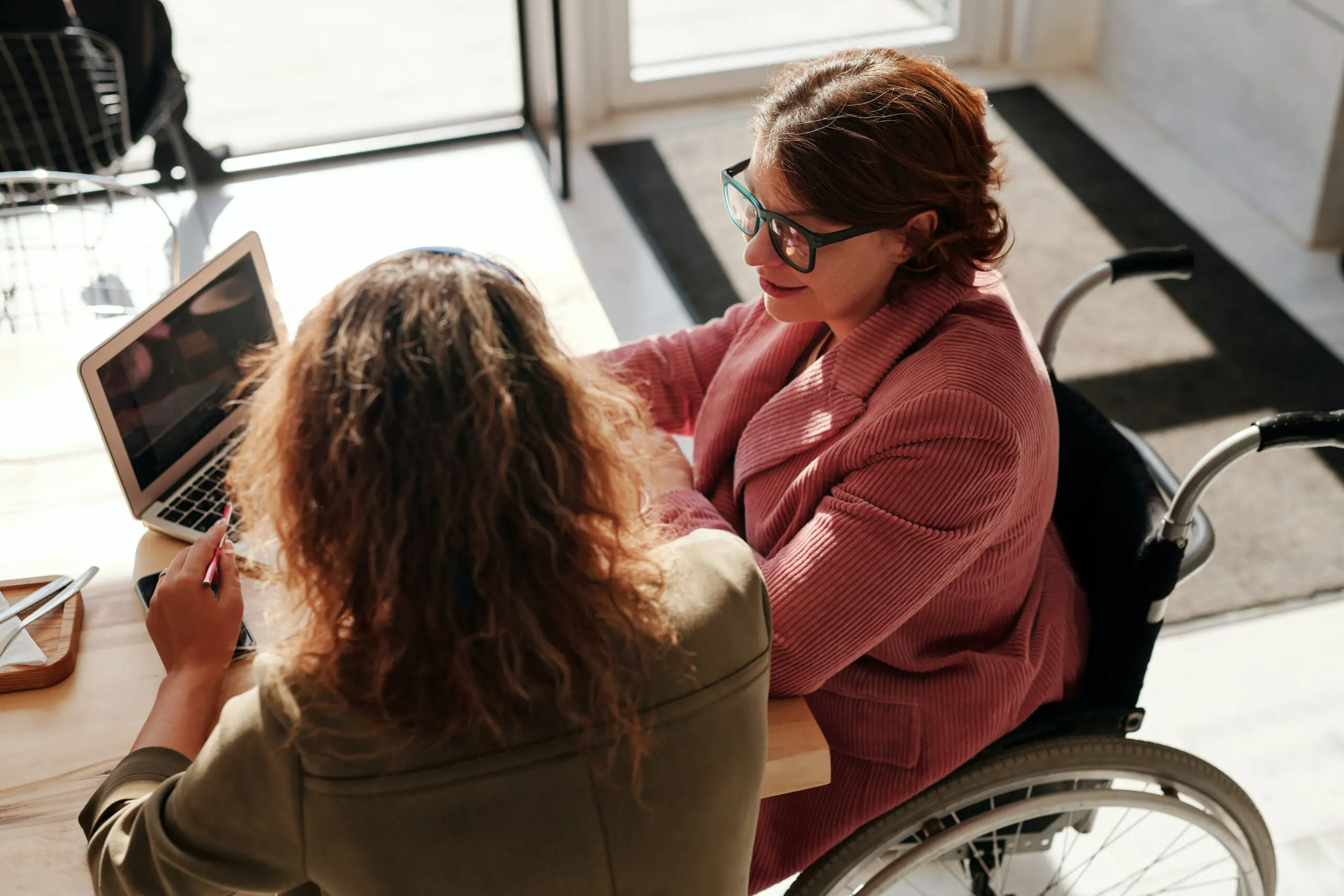 Two people looking at a laptop. One is in a wheelchair