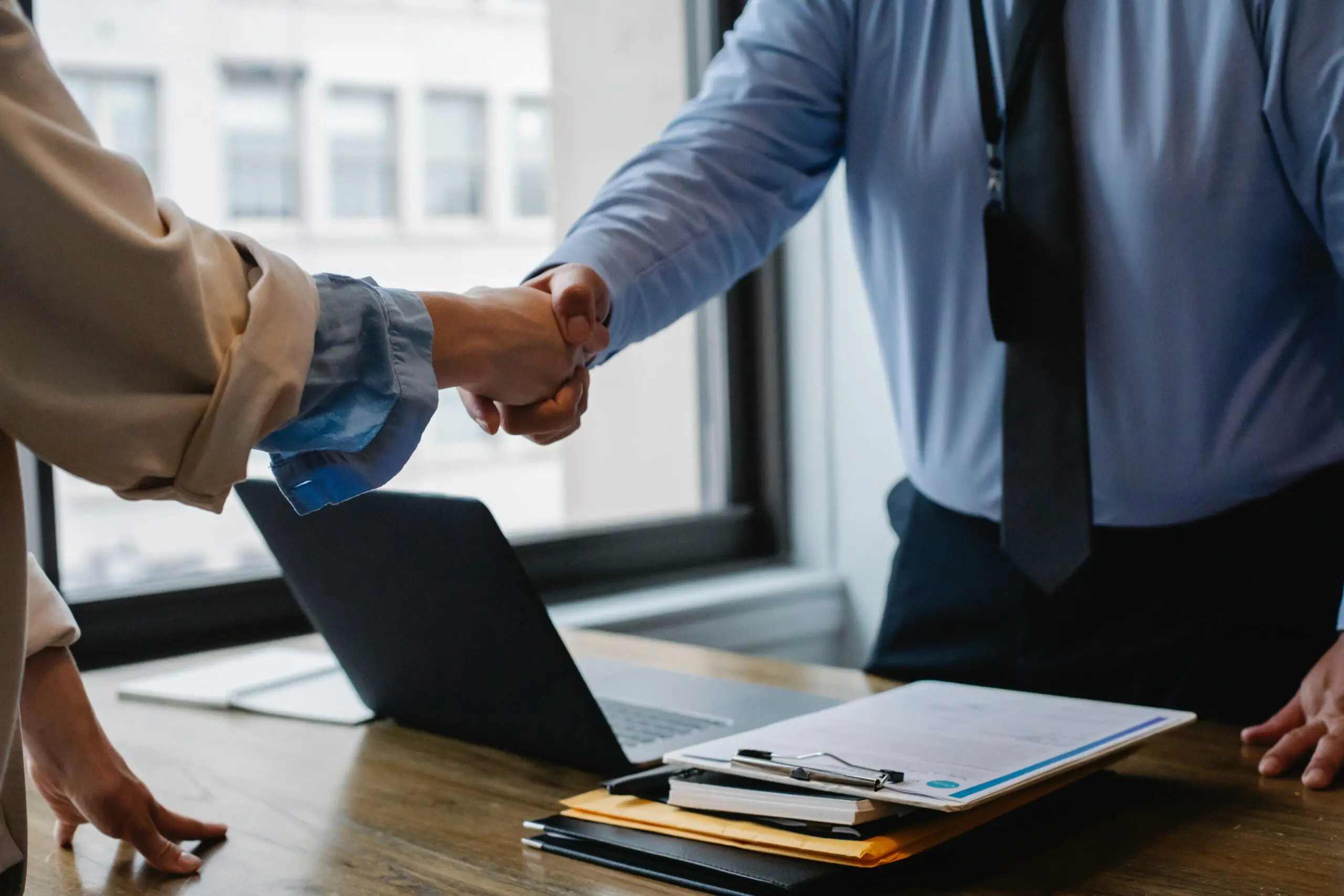 Two people shaking hands over a table