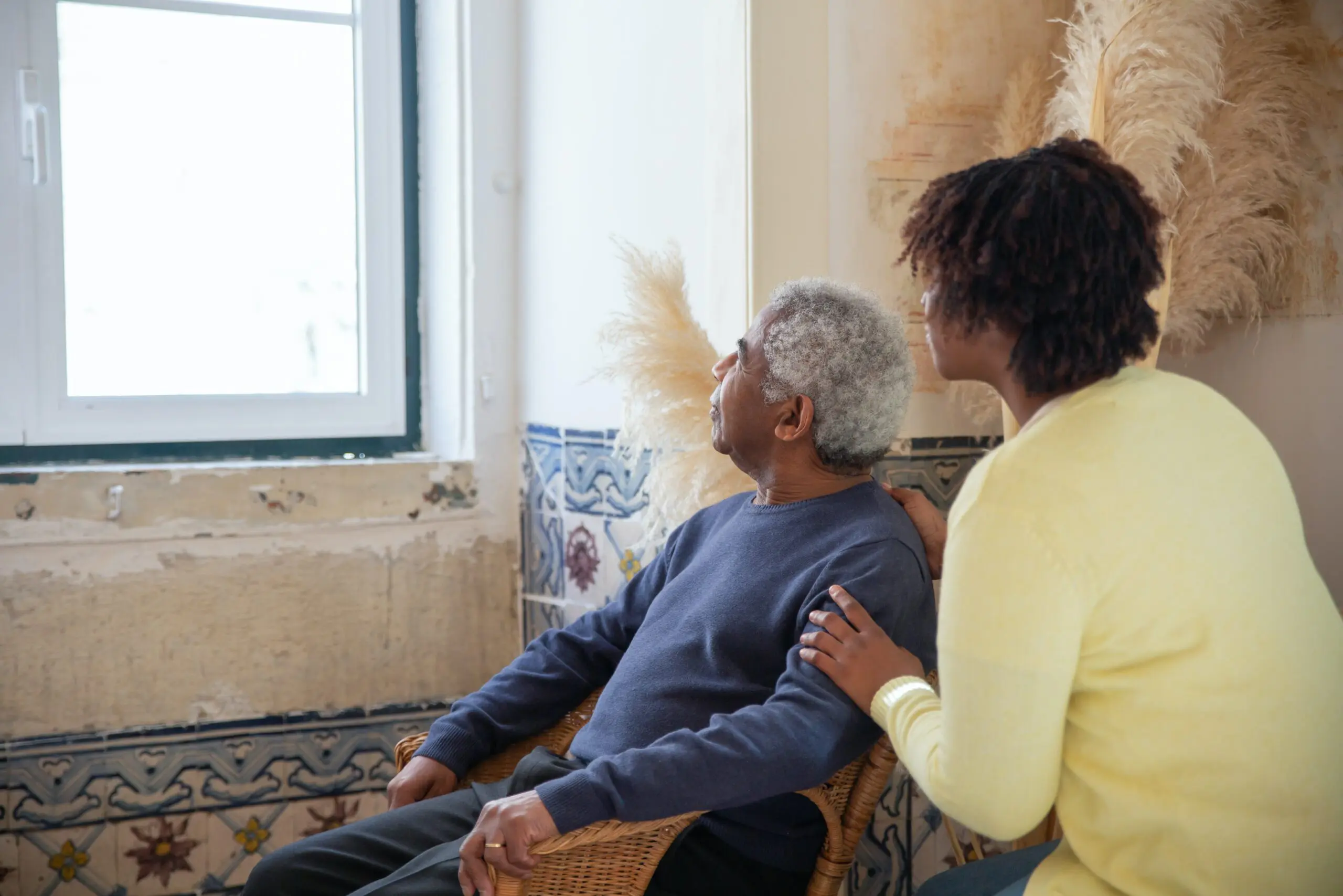 Two people, one sat down, looking out of the window
