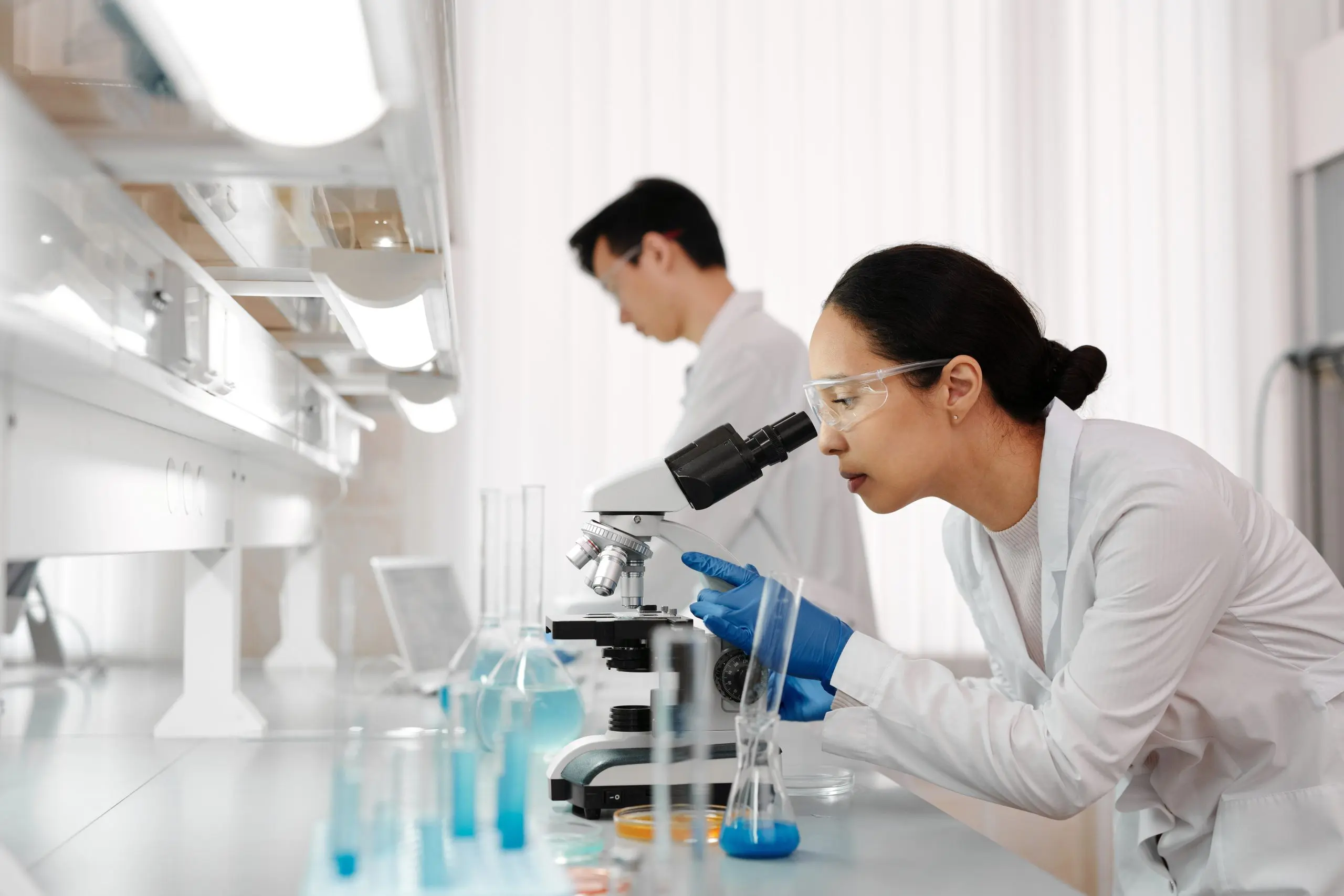 A lab, someone in the foreground looking through a microscope
