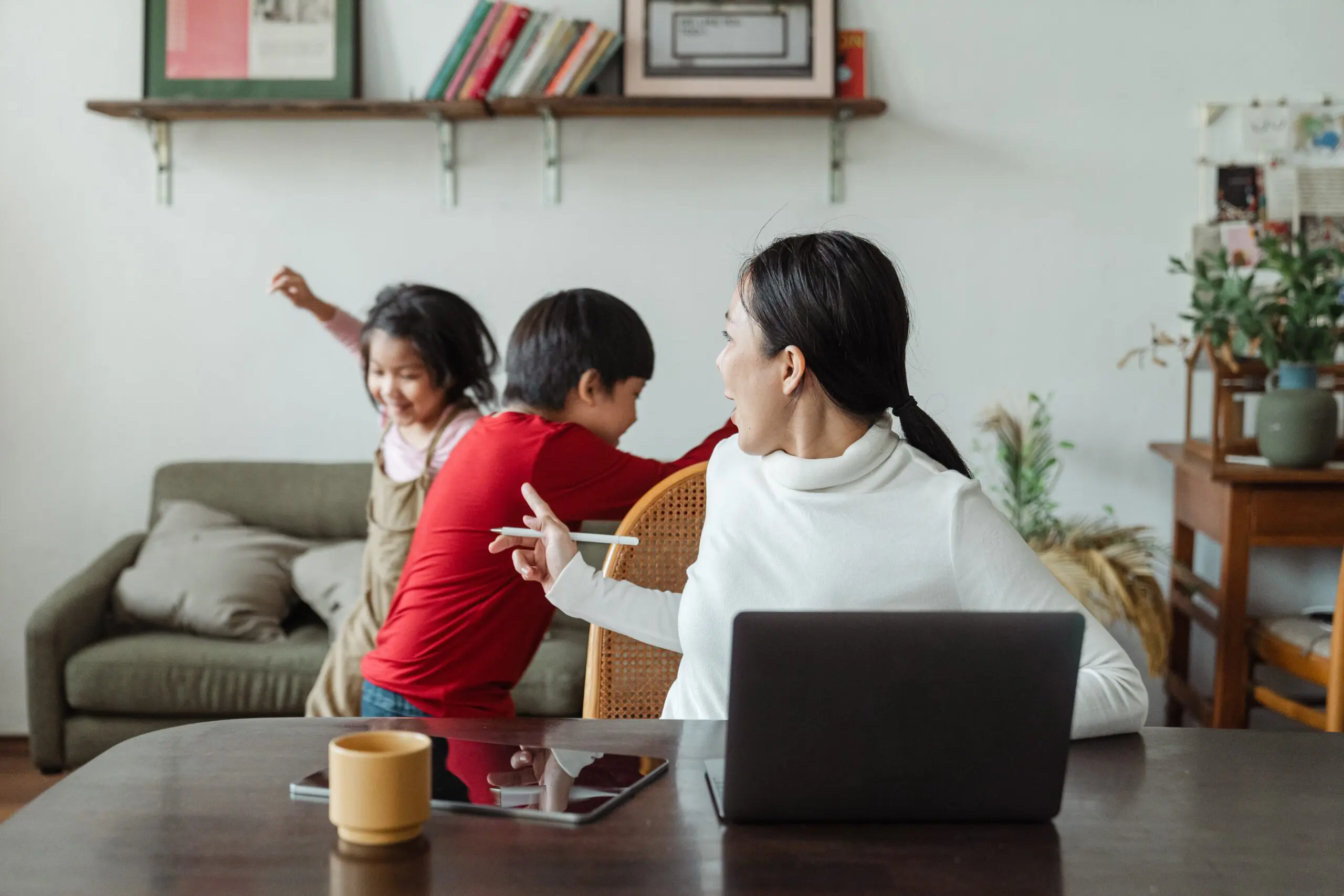 A woman on a laptop turning around to look at running children