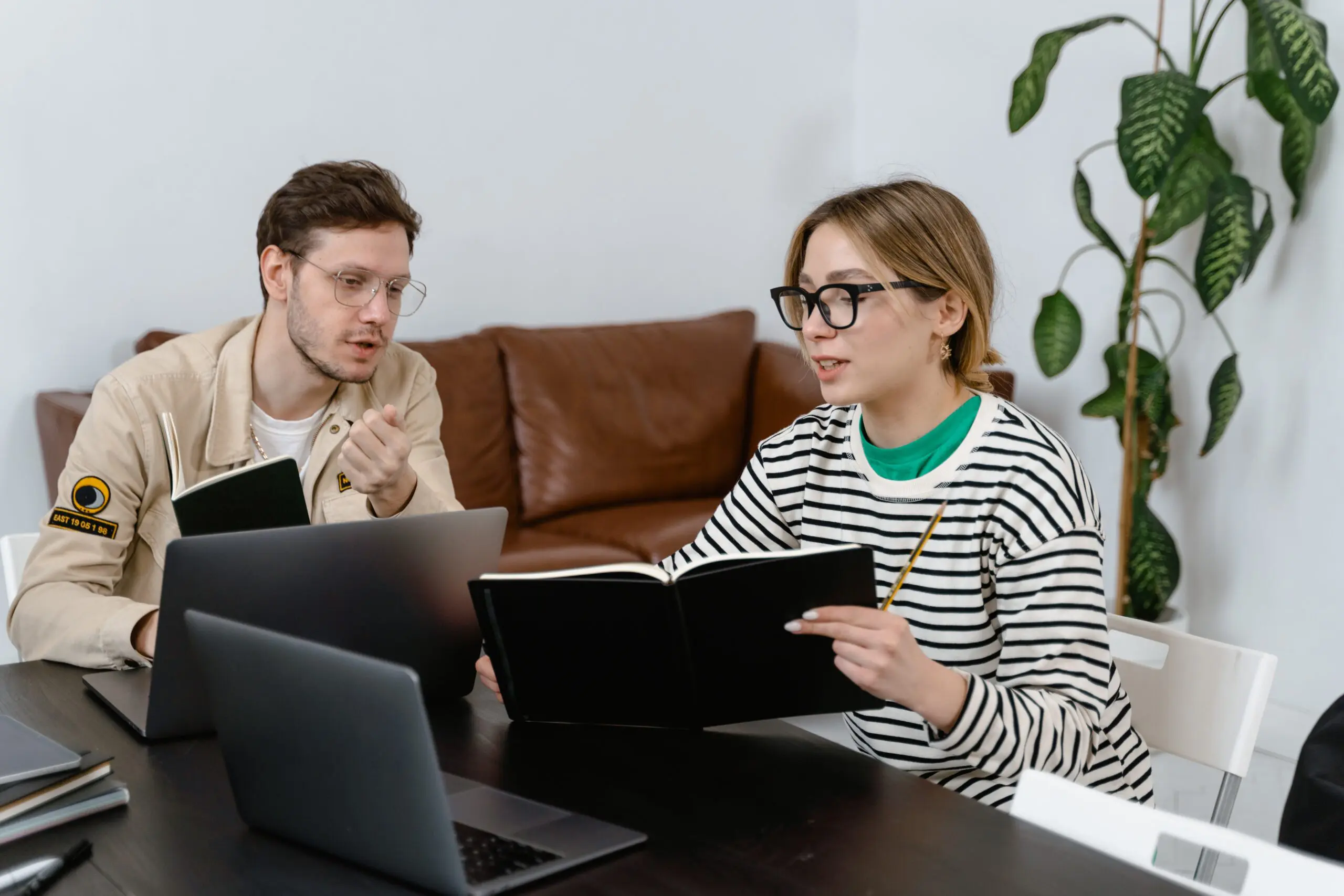 Two people working on laptops showing each other something