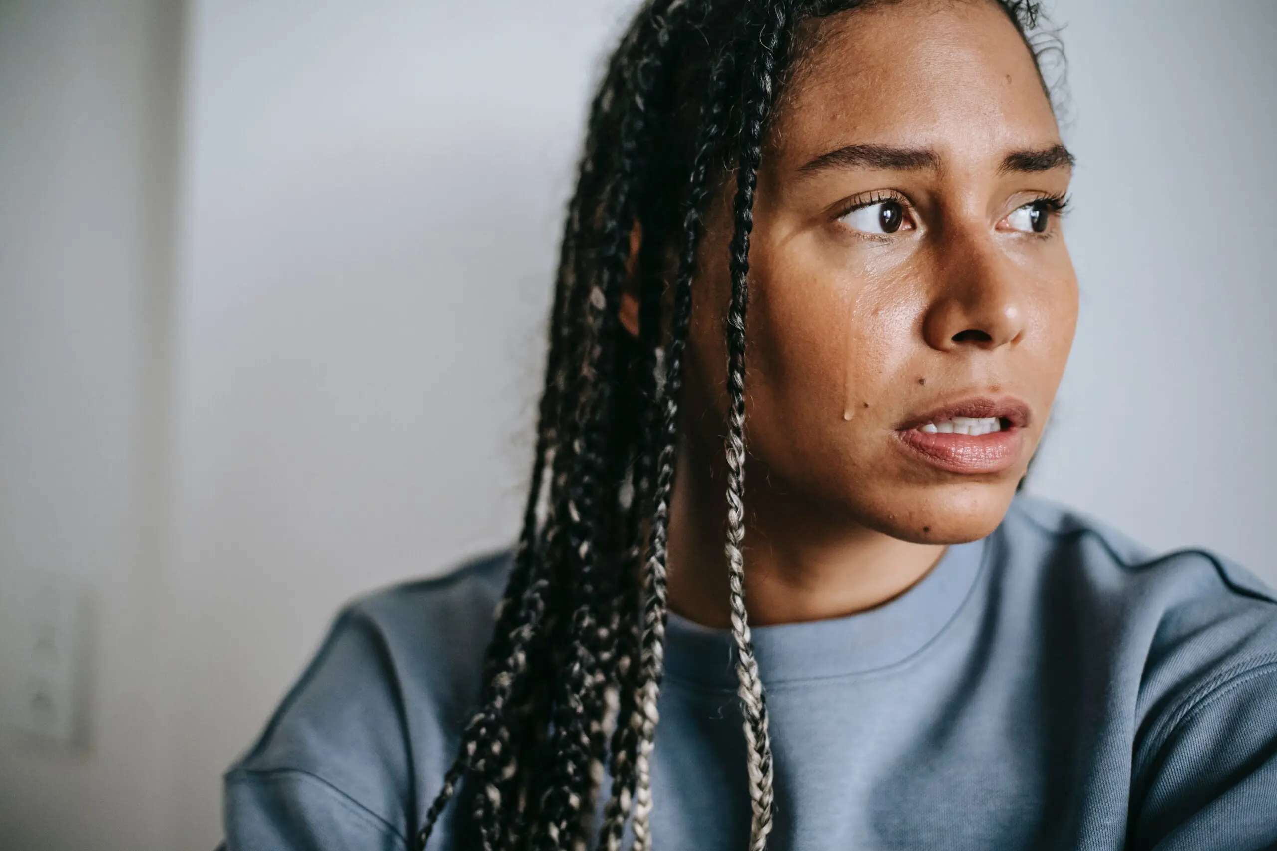 A woman looking into the distance, with a tear rolling down her face