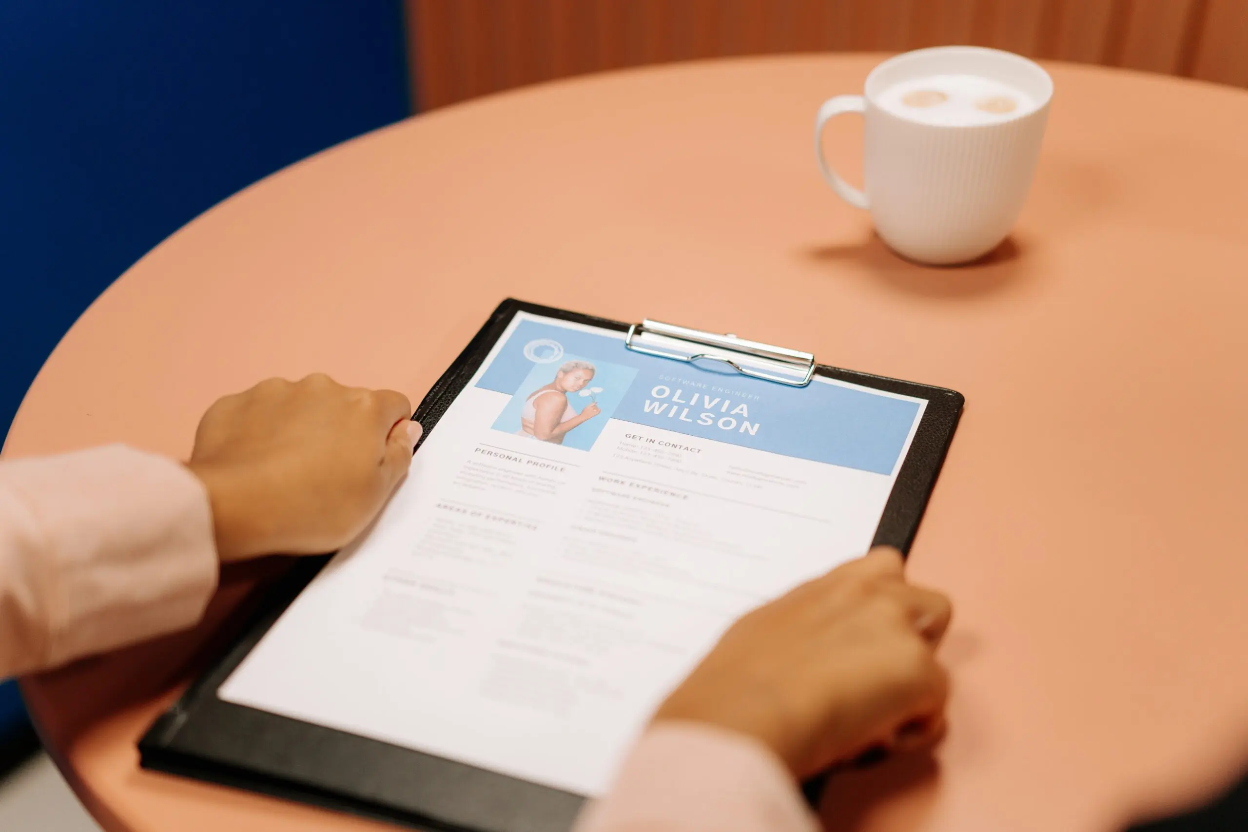 A pair of hands holding a clipboard with a CV on it