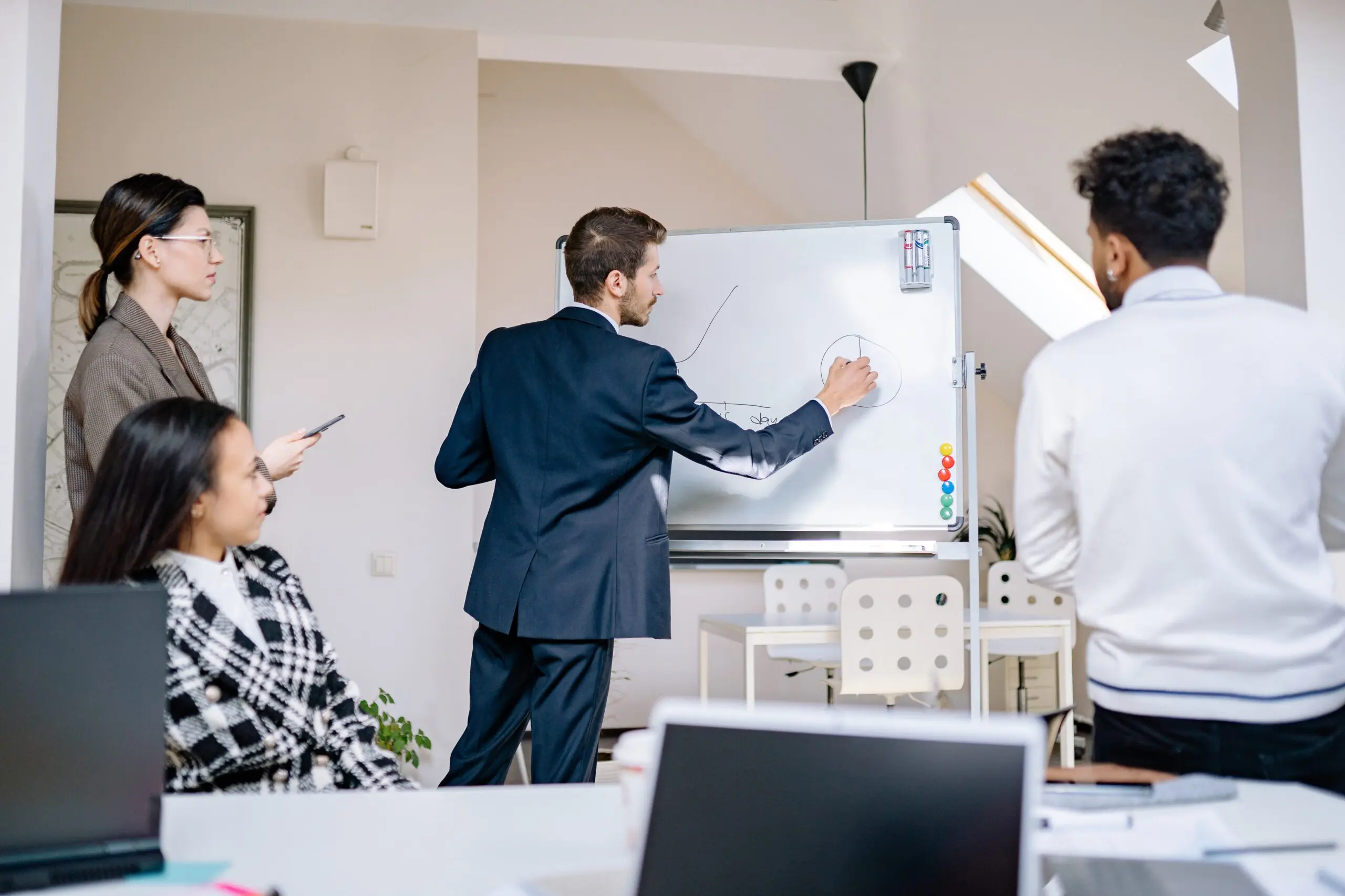 Someone drawing on a whiteboard while three people look on
