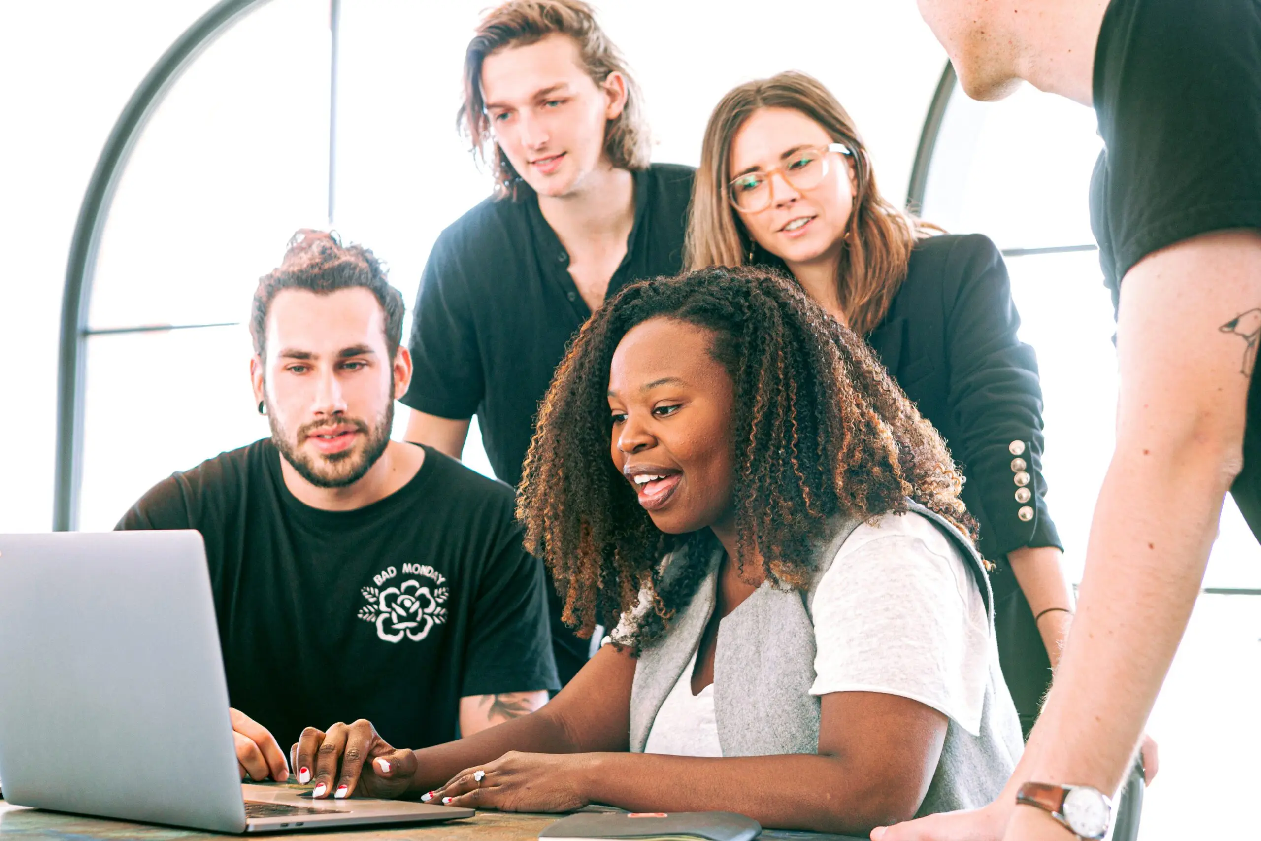 Five people gathered around a laptop looking at the screen