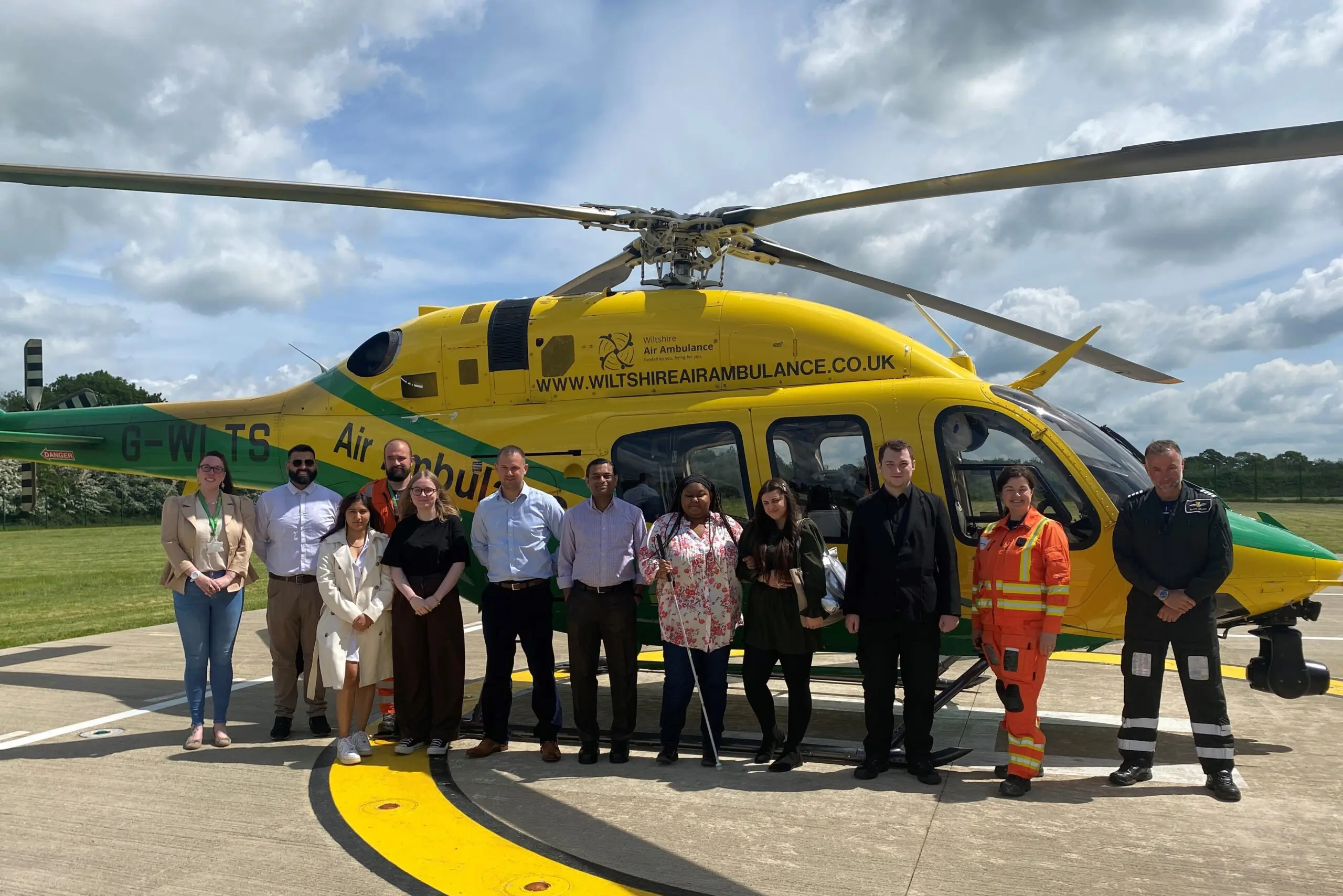 A collection of people in front of a Wiltshire Air Ambulance