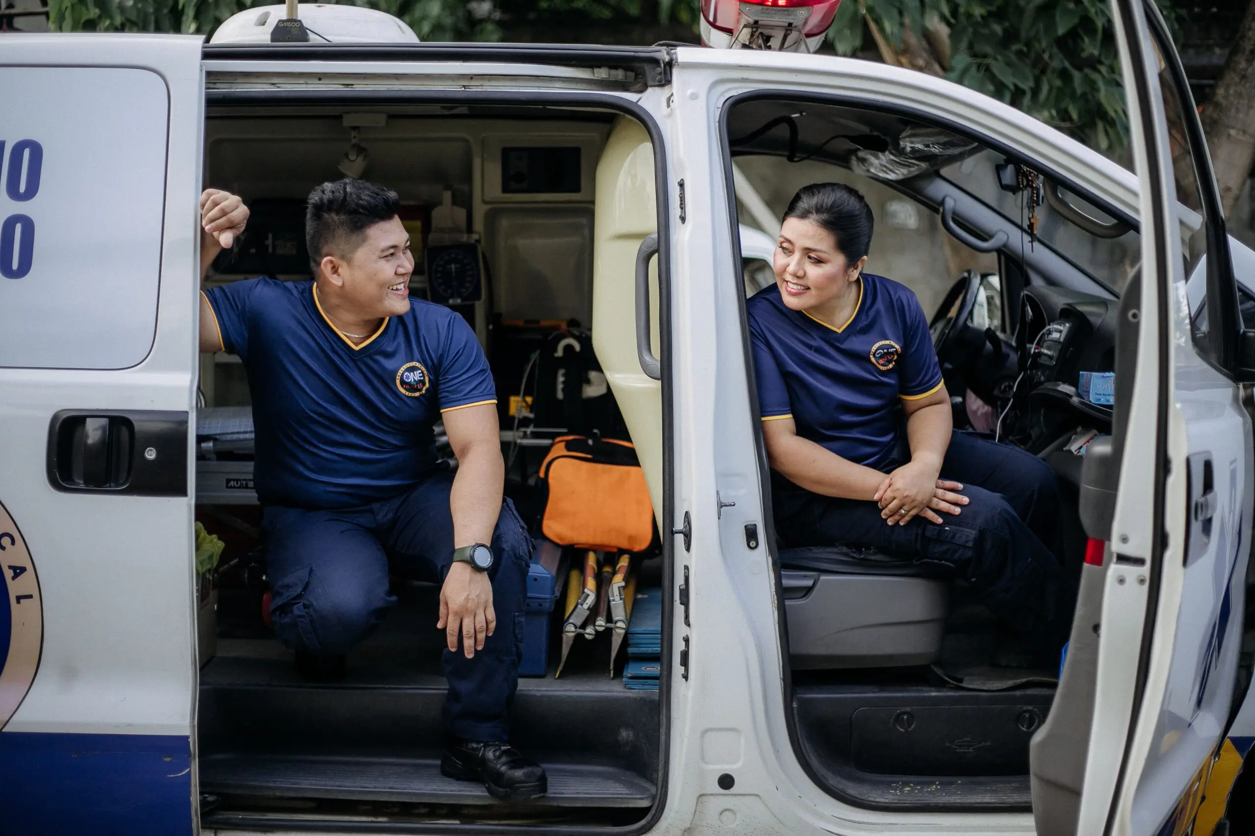 Two people inside an ambulance talking to each other out of the open doors
