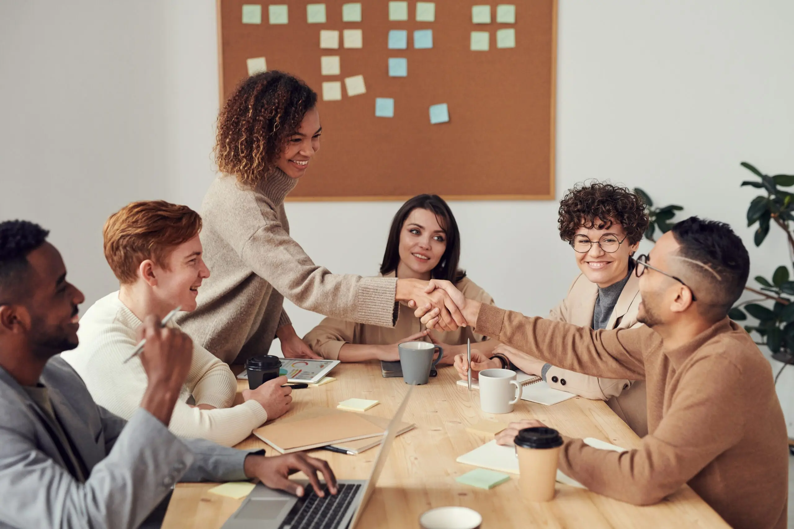 Six people around a table, two of them are shaking hands