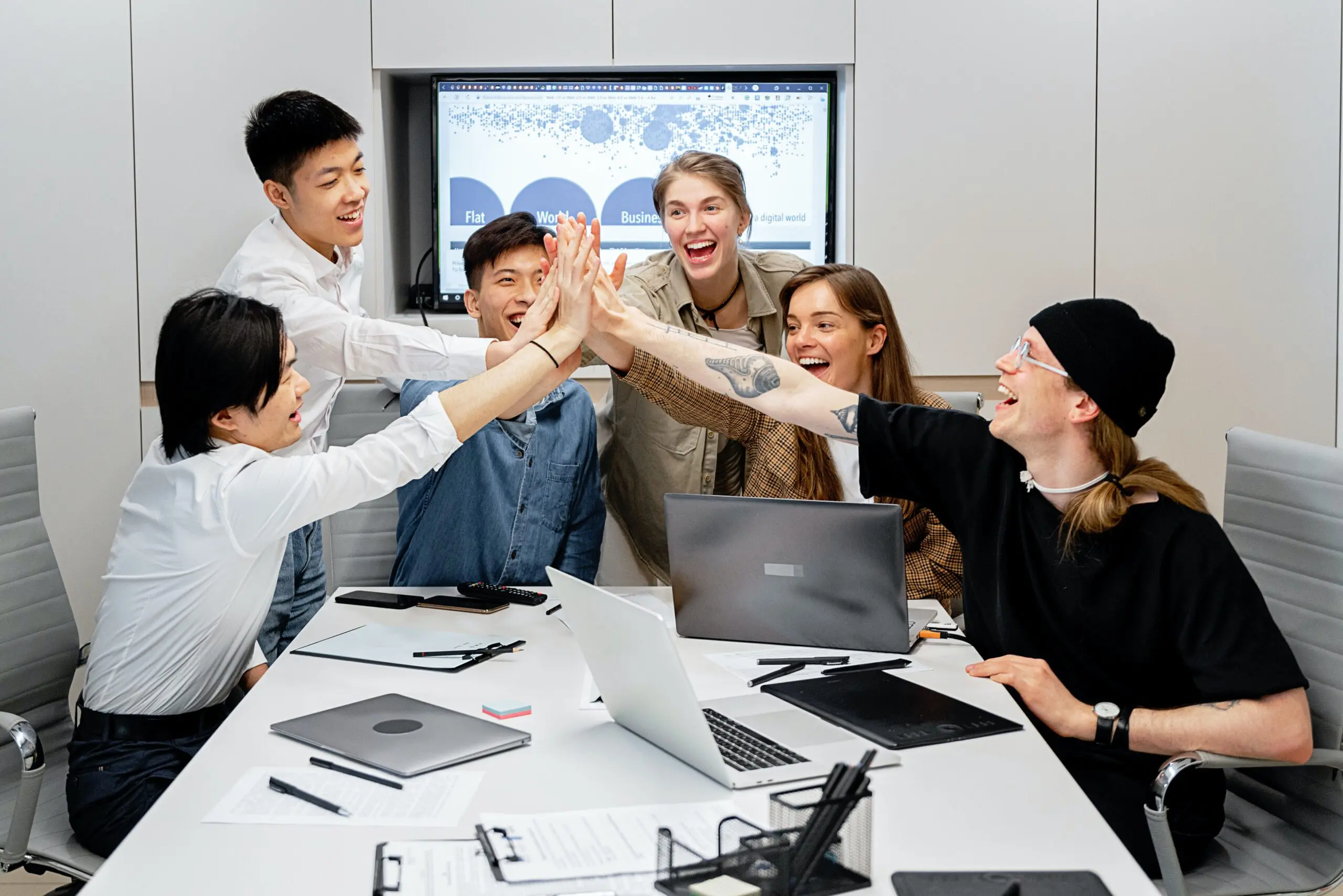 Six people performing a shared high-five over a table