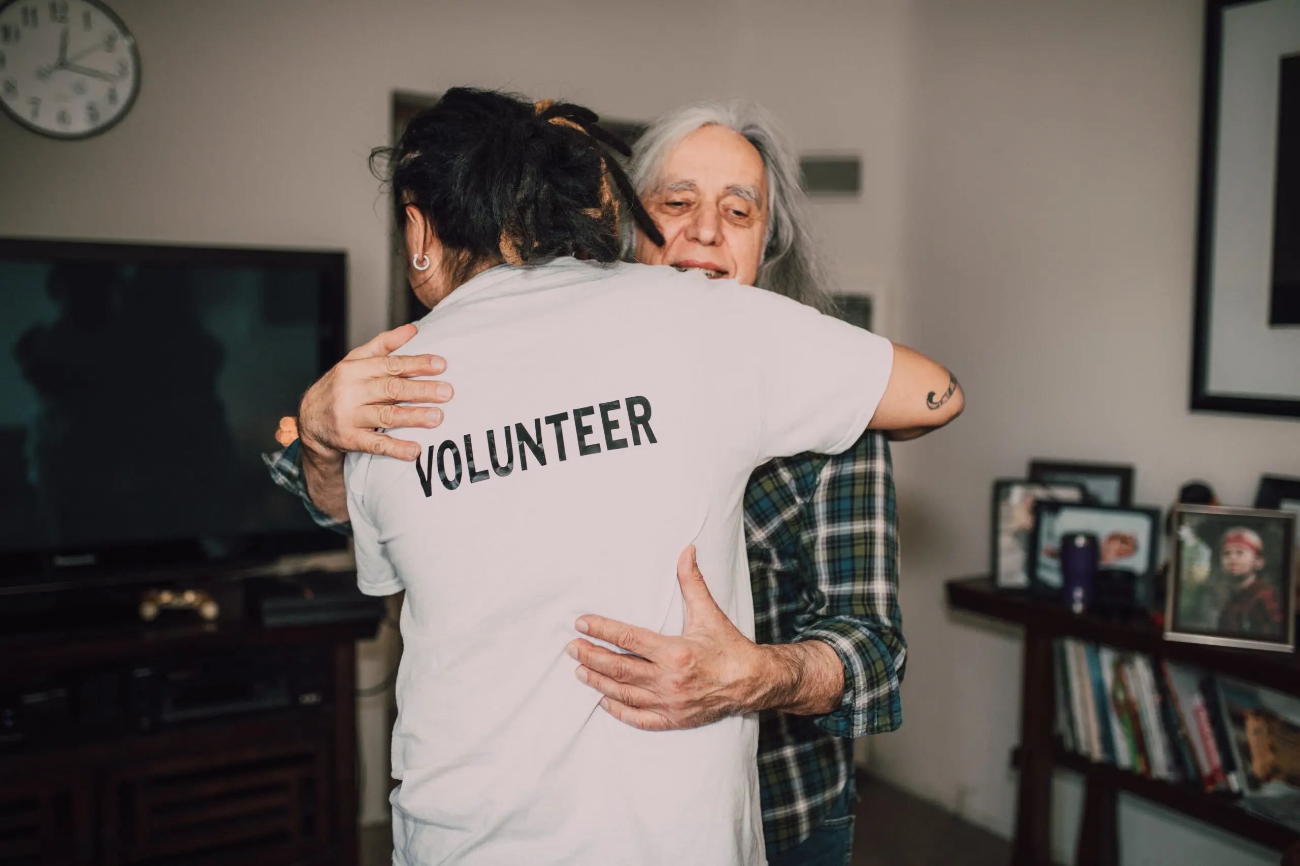 Two people hugging, one wearing a t-shirt with the word 'volunteer' on it