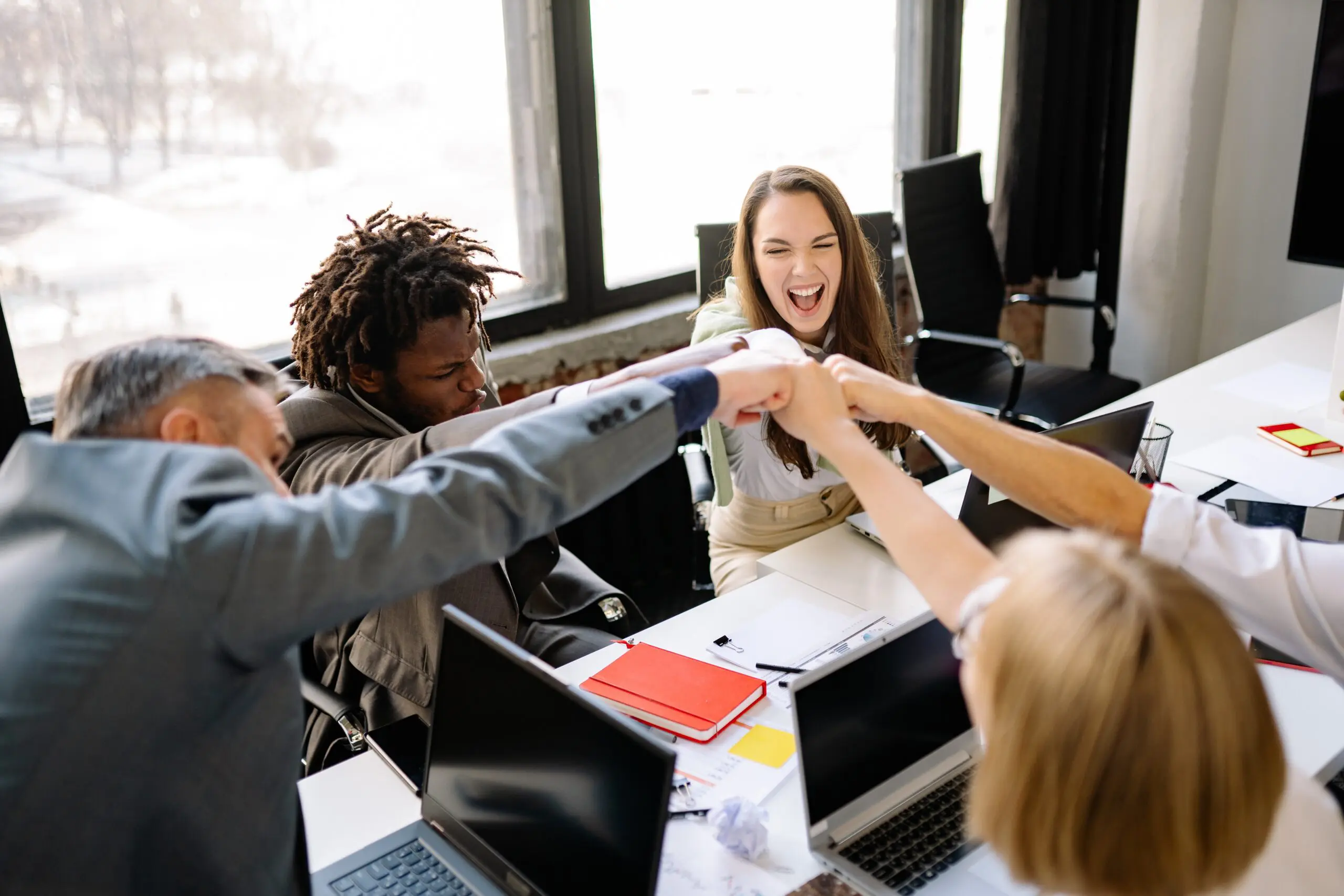 Five people all fistbumping over a desk