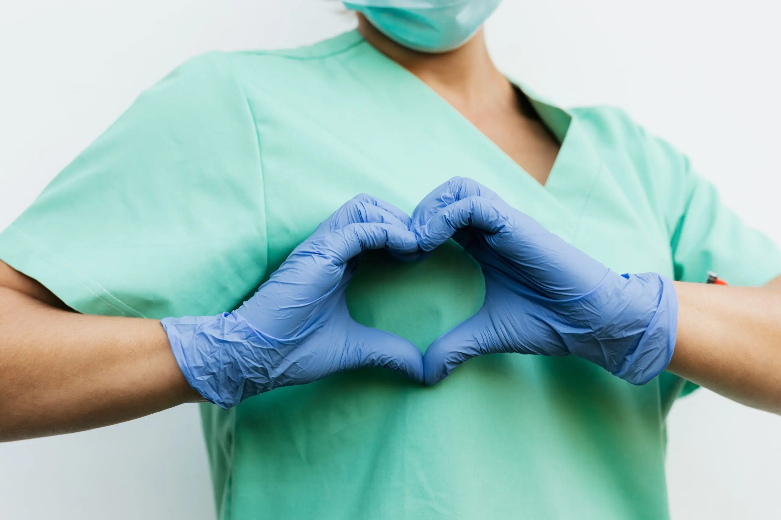 Someone in scrubs making a heart with their hands