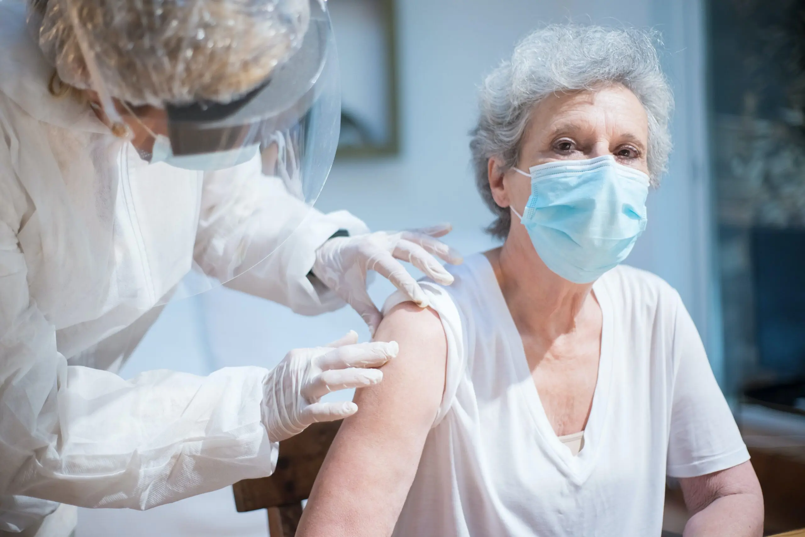 Woman getting an injection by nurse wearing PPE
