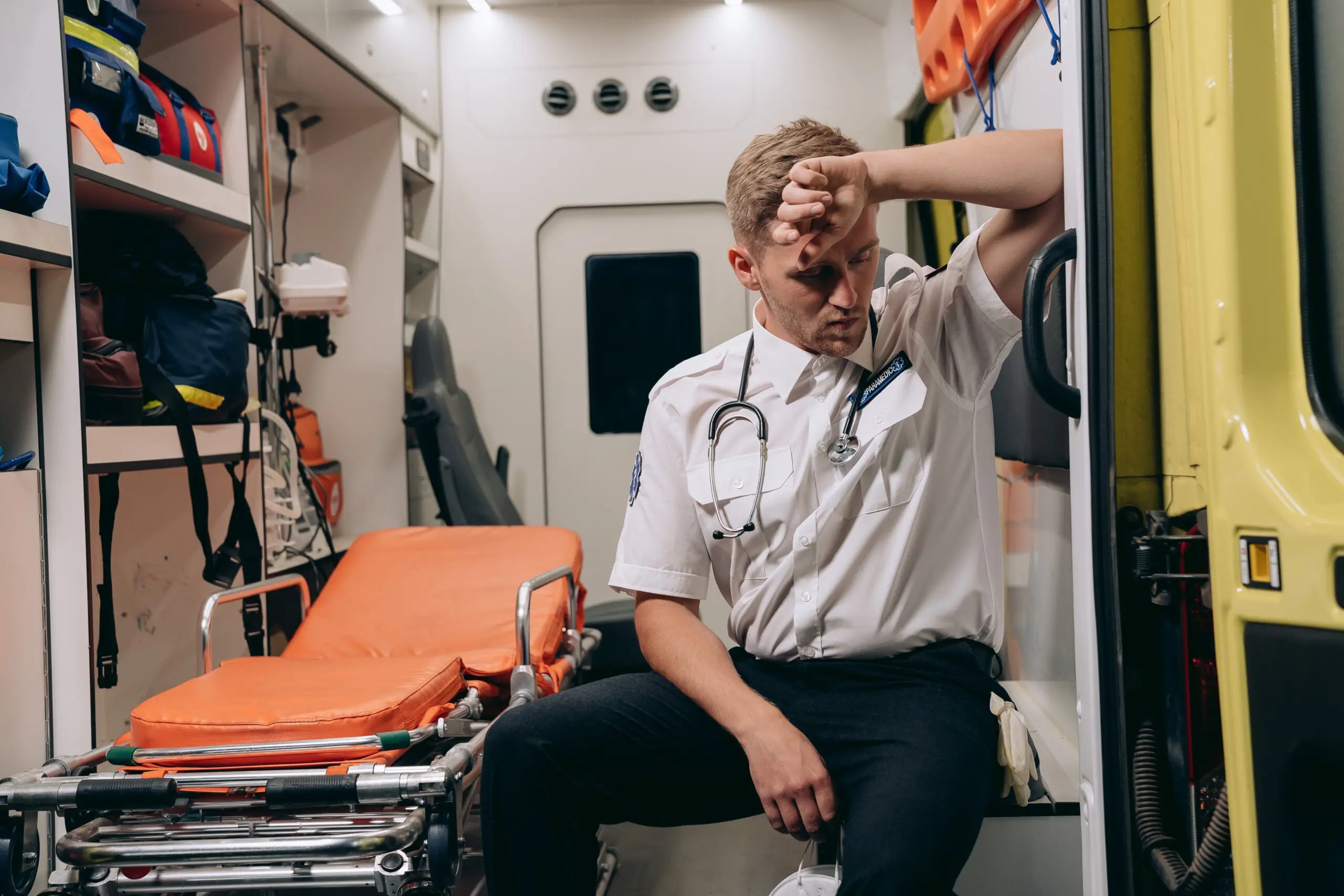 A paramedic sat in the back of an ambulance looking tired