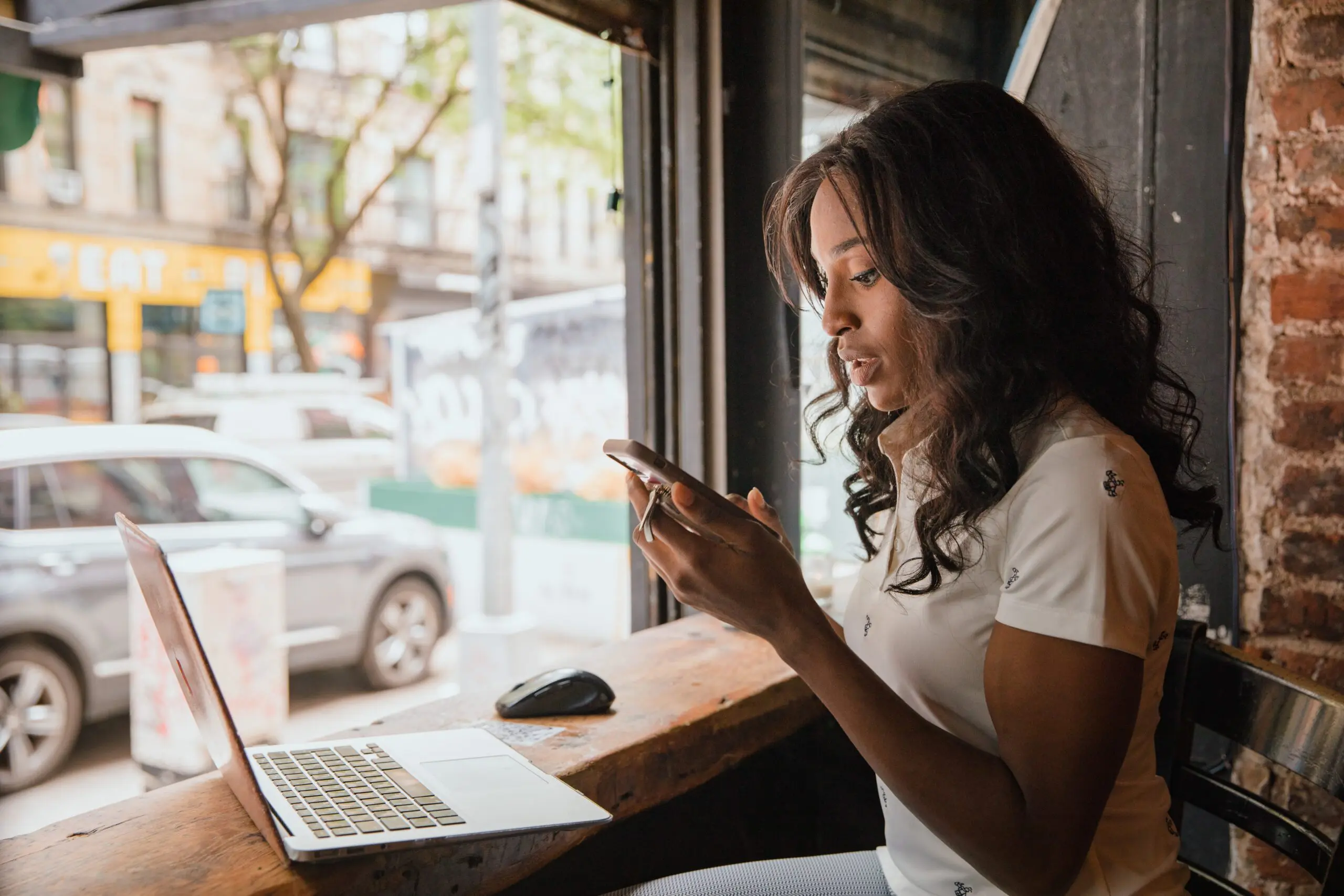 Someone on their phone while also on their laptop