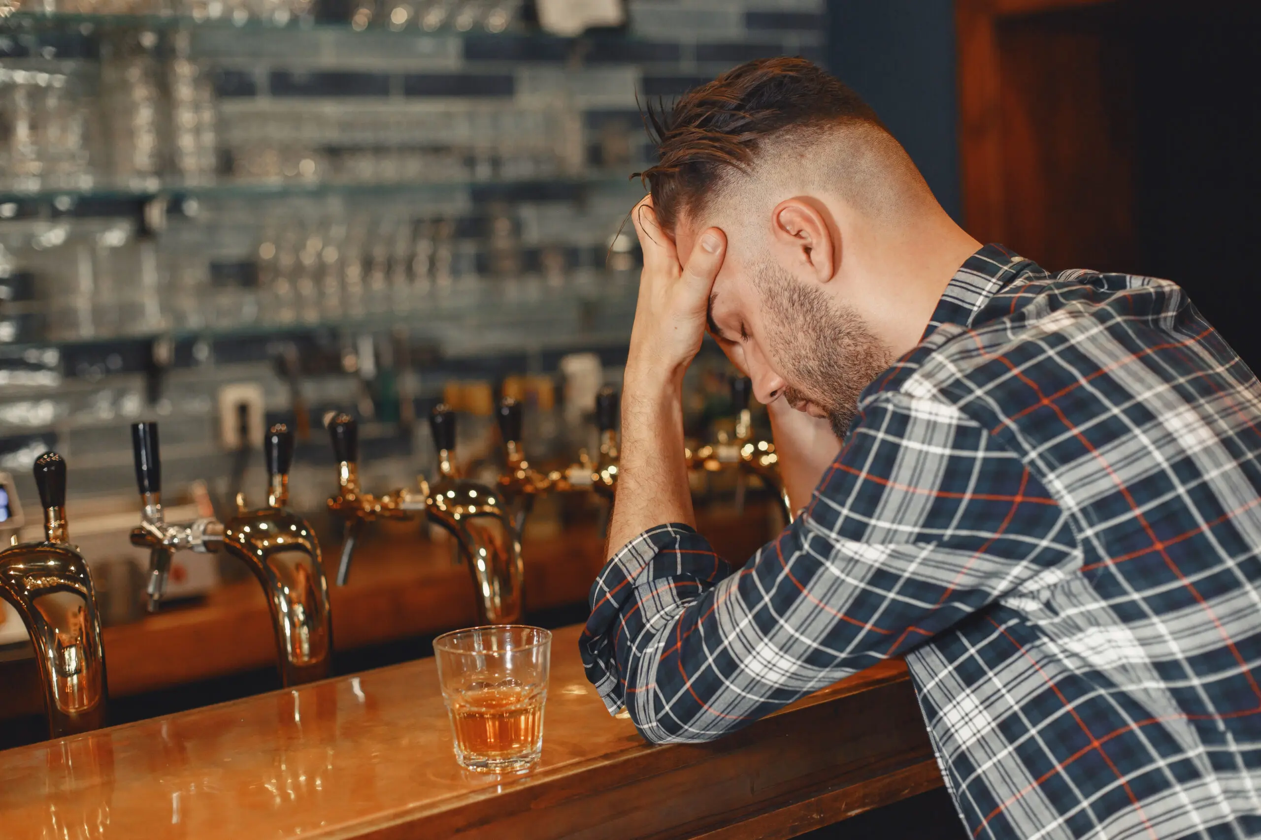 Man holding his head in his hands at a bar