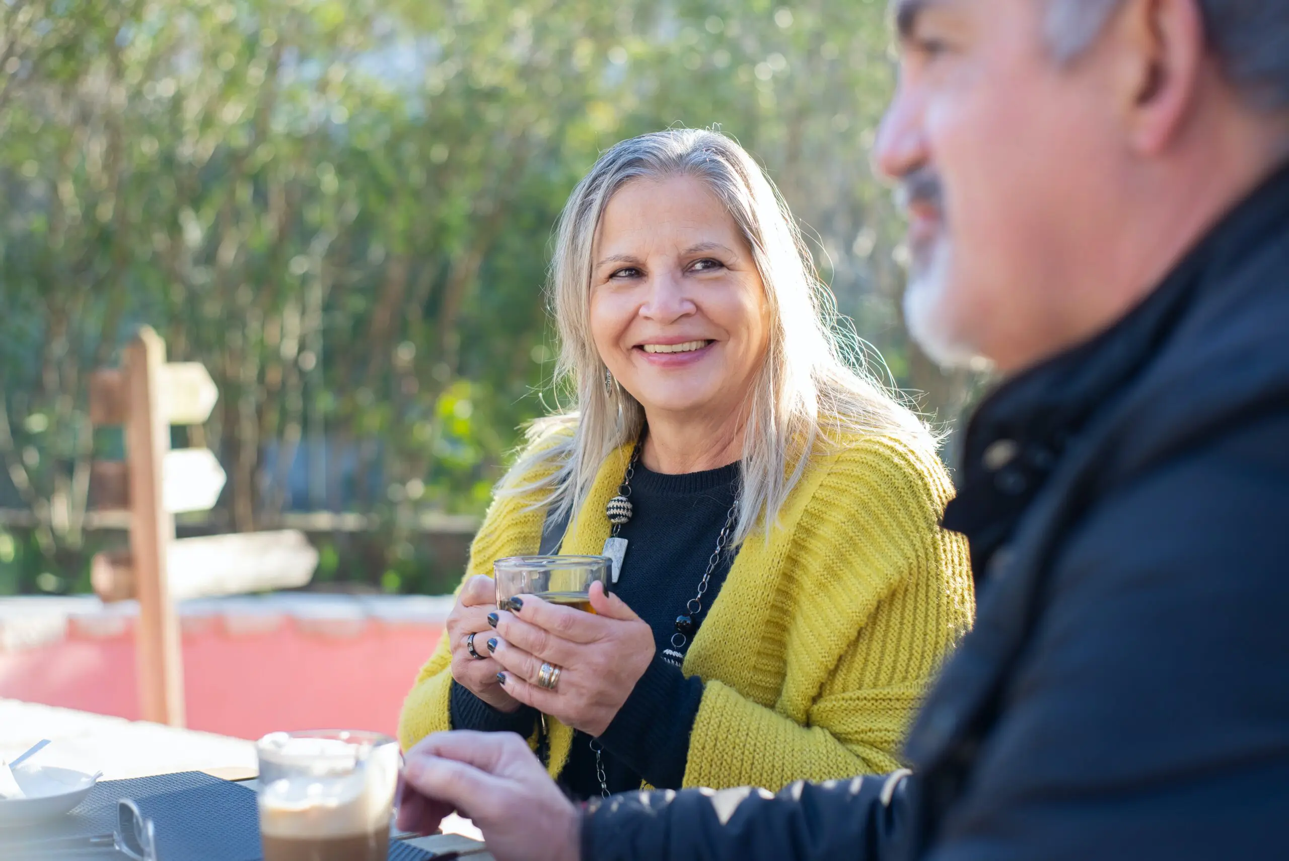 A woman smiling while drinking coffee with her care worker