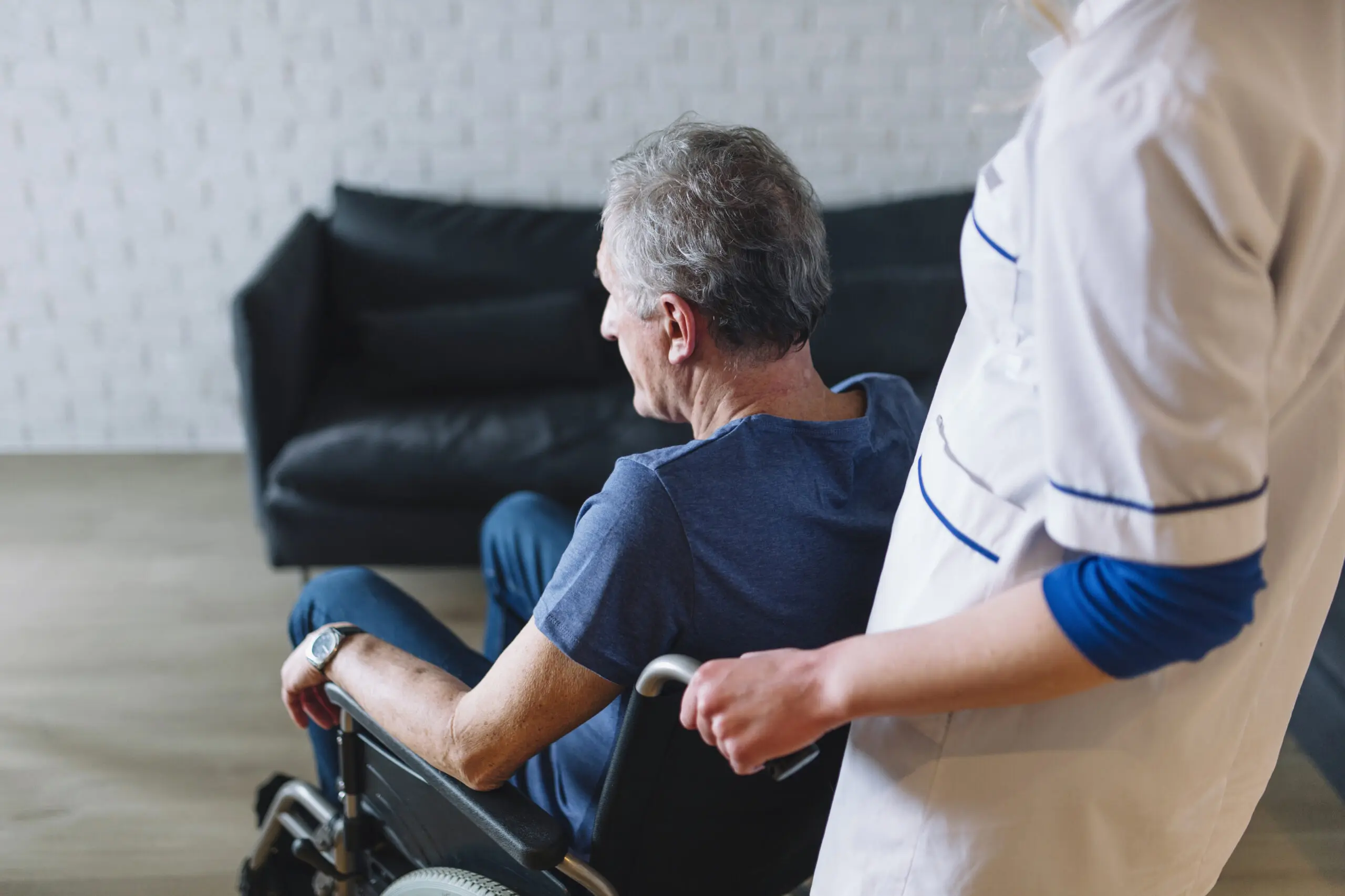 A nurse pushing an elderly man in a wheelchair