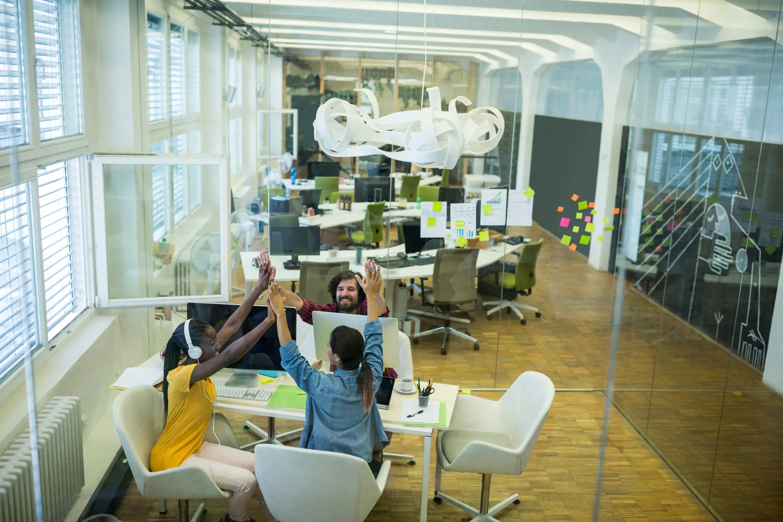 Group of graphic designers giving high five to each other in office