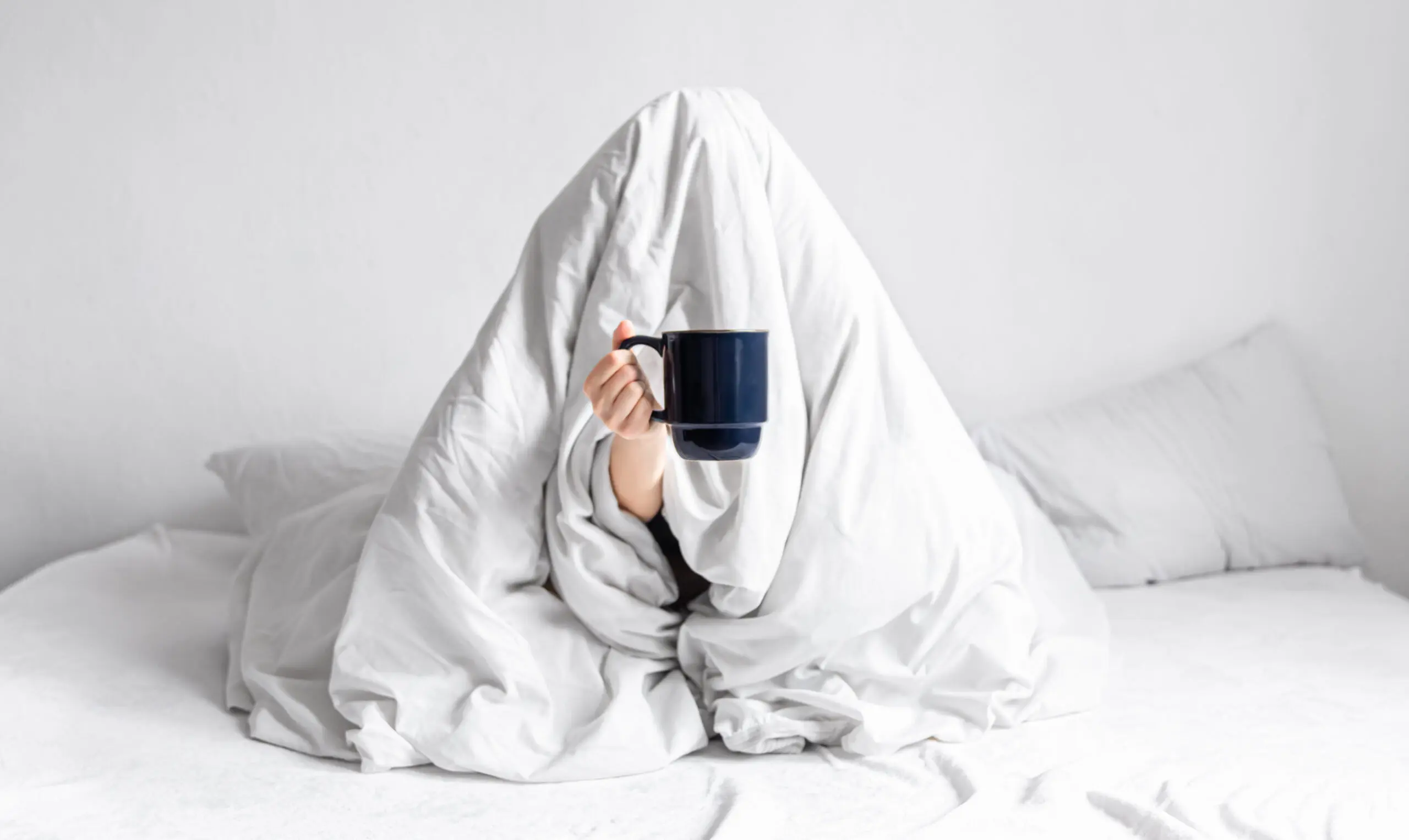 a-woman-wrapped-in-a-blanket-holding-a-hot-drink