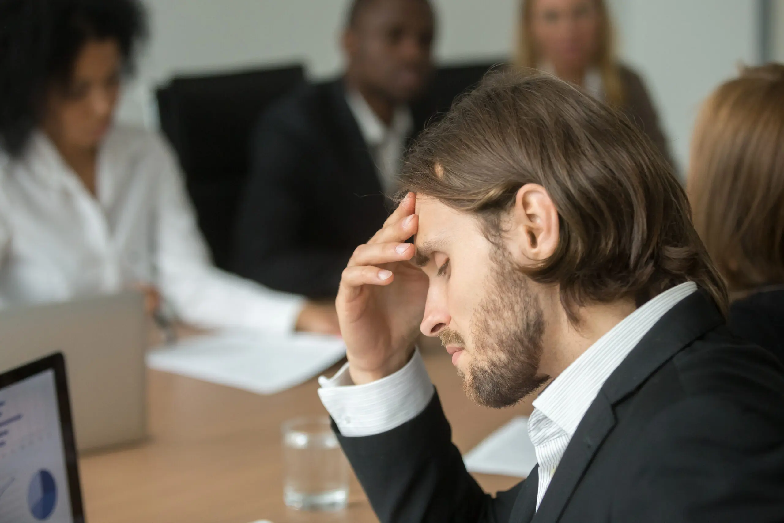 frustrated-tired-leader-having-a-strong-headache-in-team-meeting