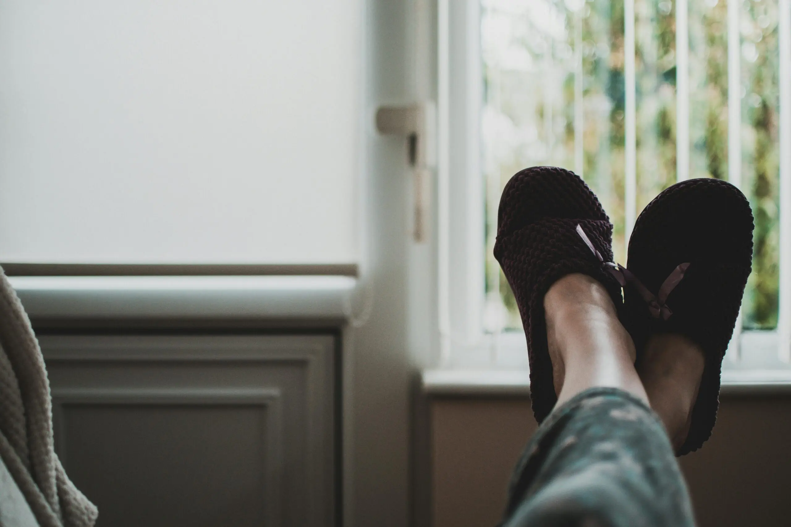 woman-wearing-slippers-with-her-feet-up-resting-on-sofa