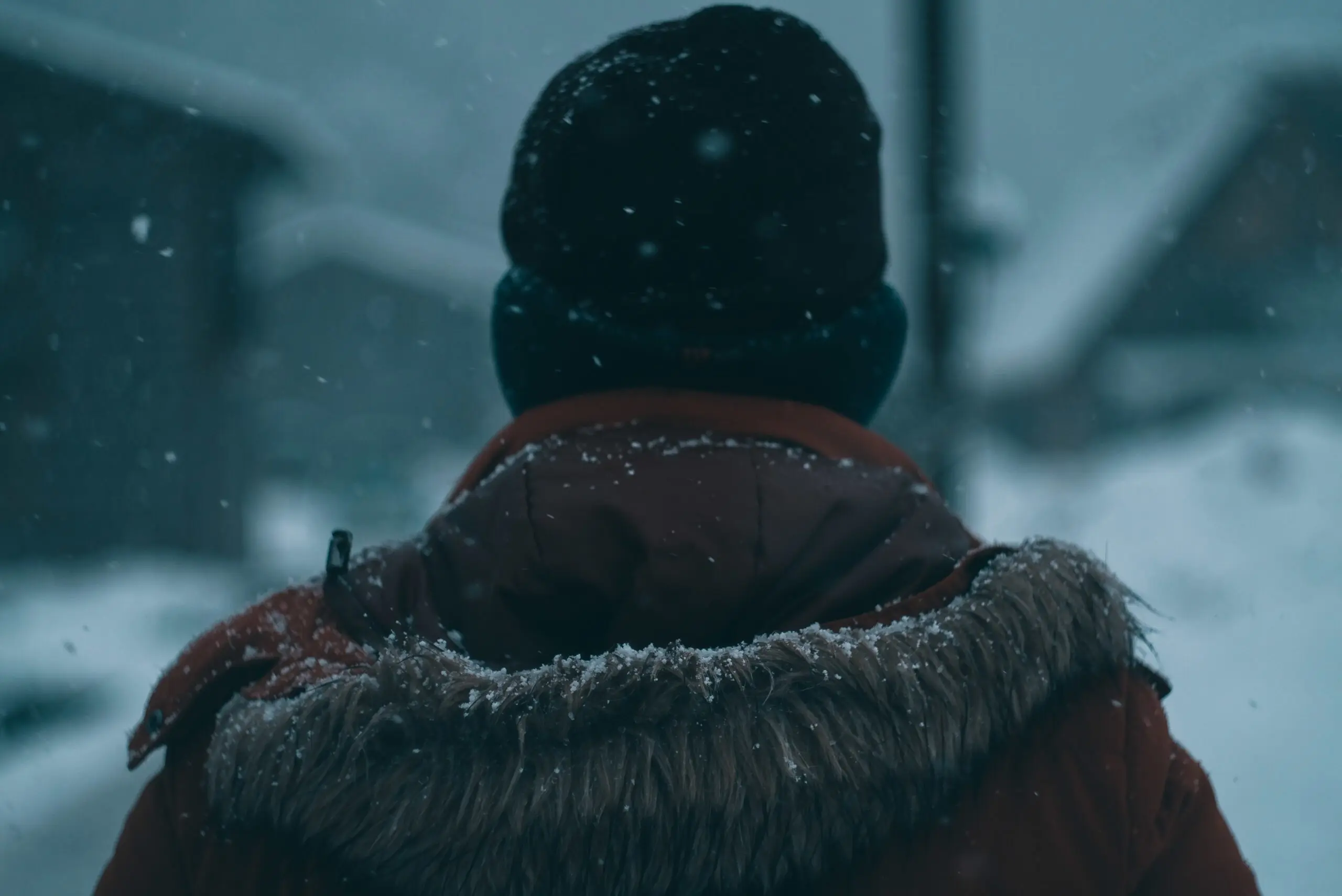 The back of a man with a hooded coat and a beanie during winter