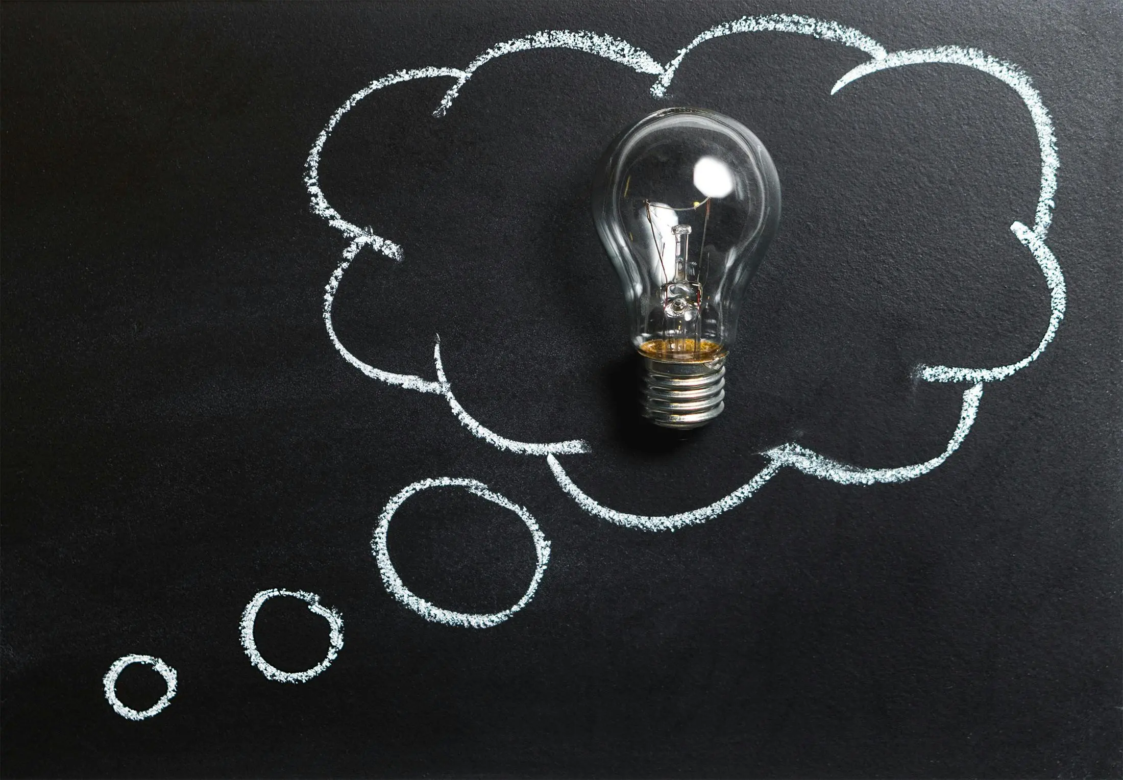 lightbulb with a chalk drawing of a thought bubble around it