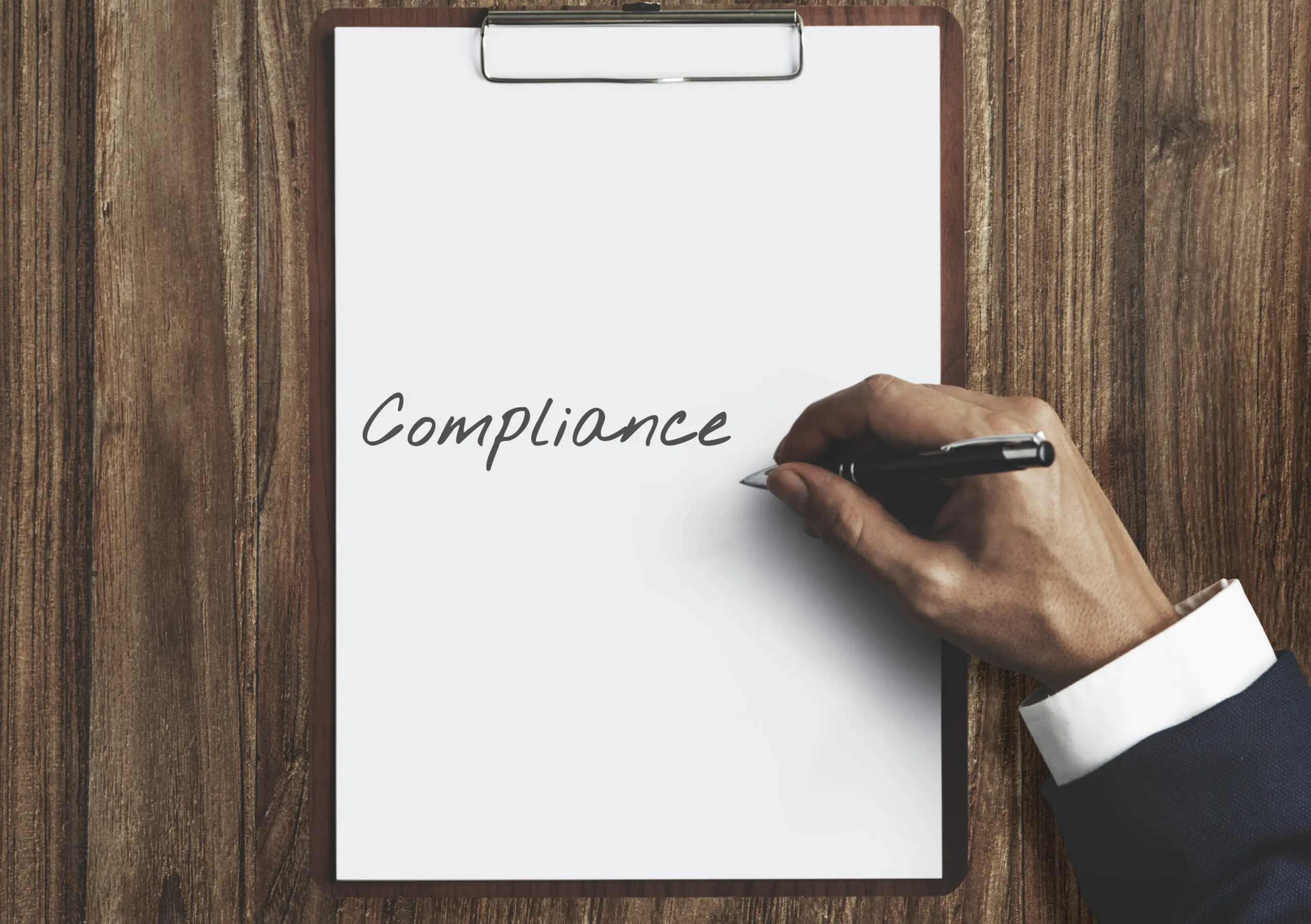 man-writing-the-word-compliance-onto-paper