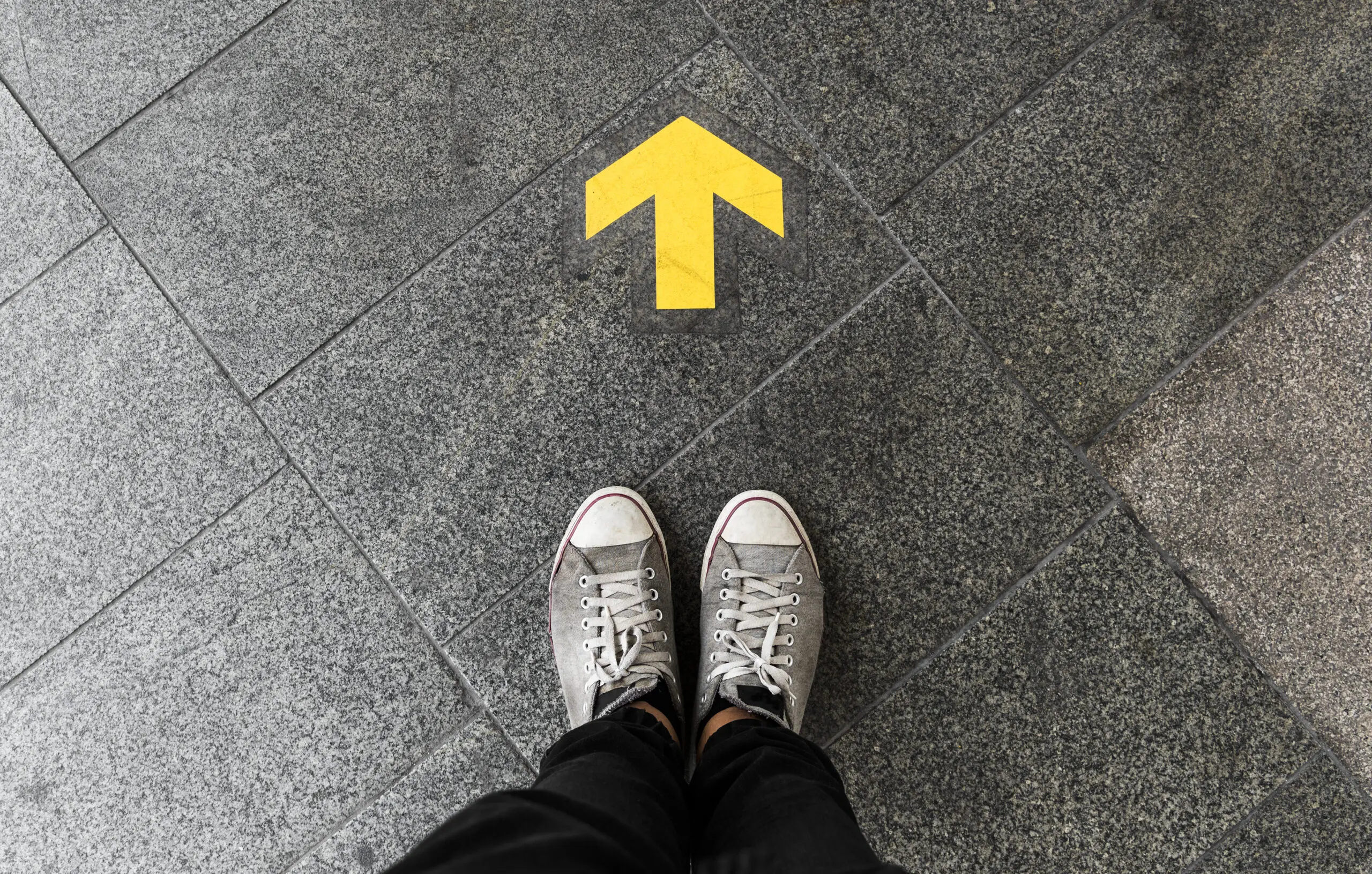 person looking down at an arrow pointing forward
